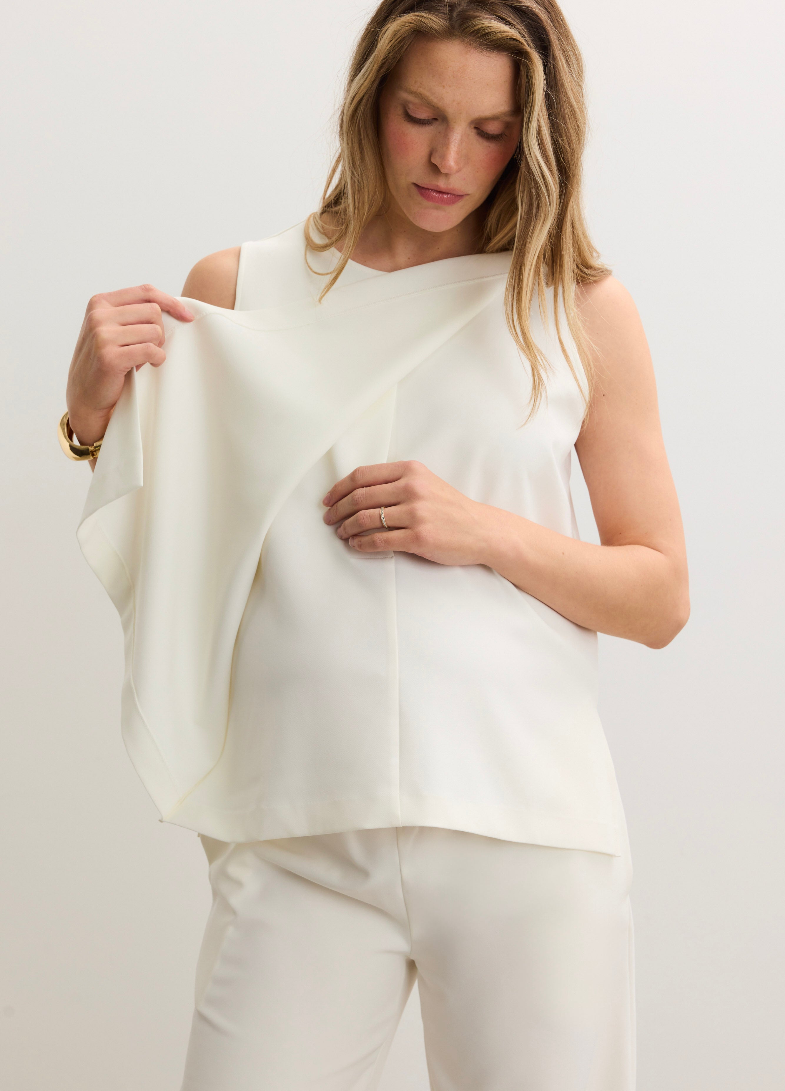 Cream-colored sleeveless nursing tank with soft, stretchy fabric and discreet front panel for easy breastfeeding access.