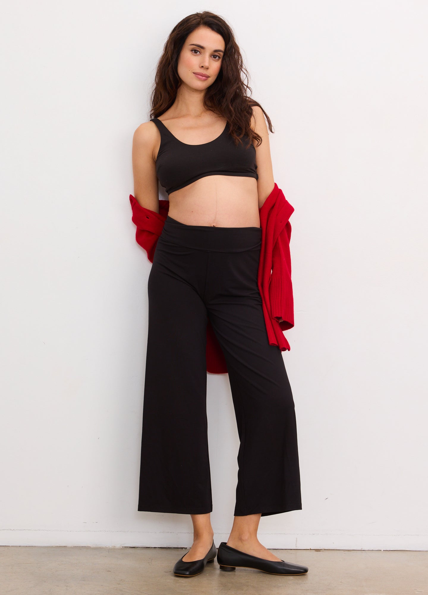 Black maternity crop pants with wide legs, soft stretchy fabric, worn with a black crop tank and red cardigan draped over.