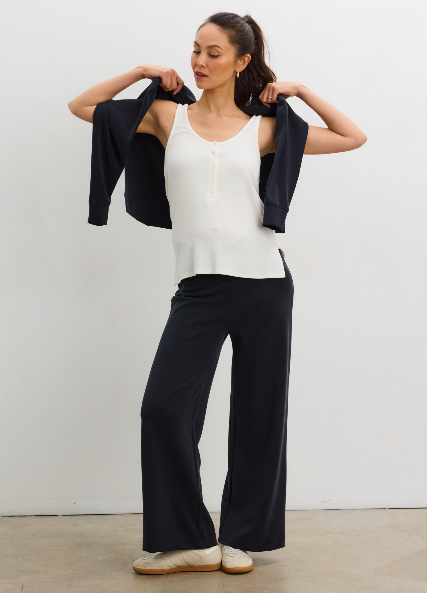 Black wide-leg maternity pants with a soft white tank top on a pregnant woman.