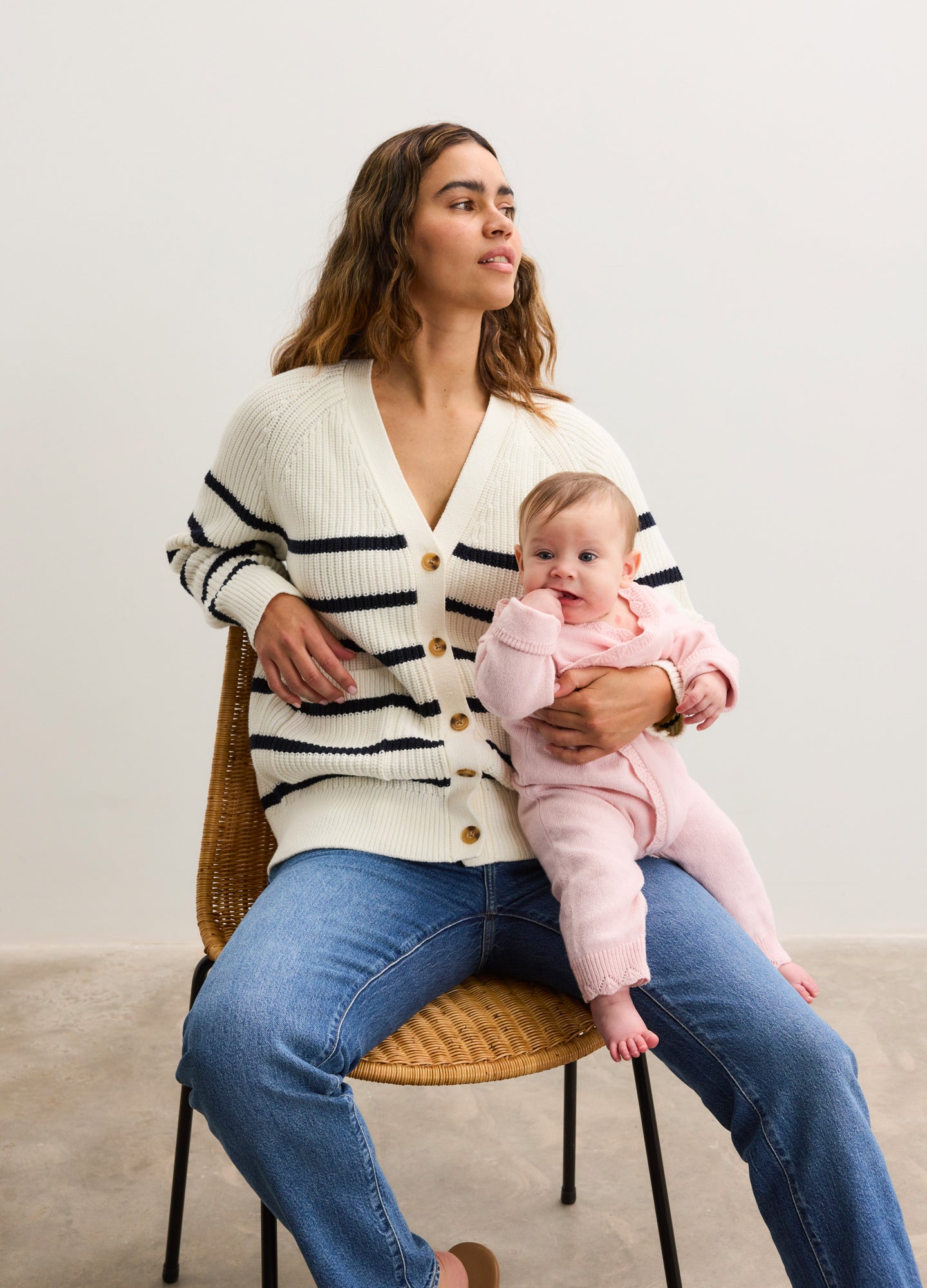 Cream-colored cardigan with black horizontal stripes, button-front, worn over maternity jeans.