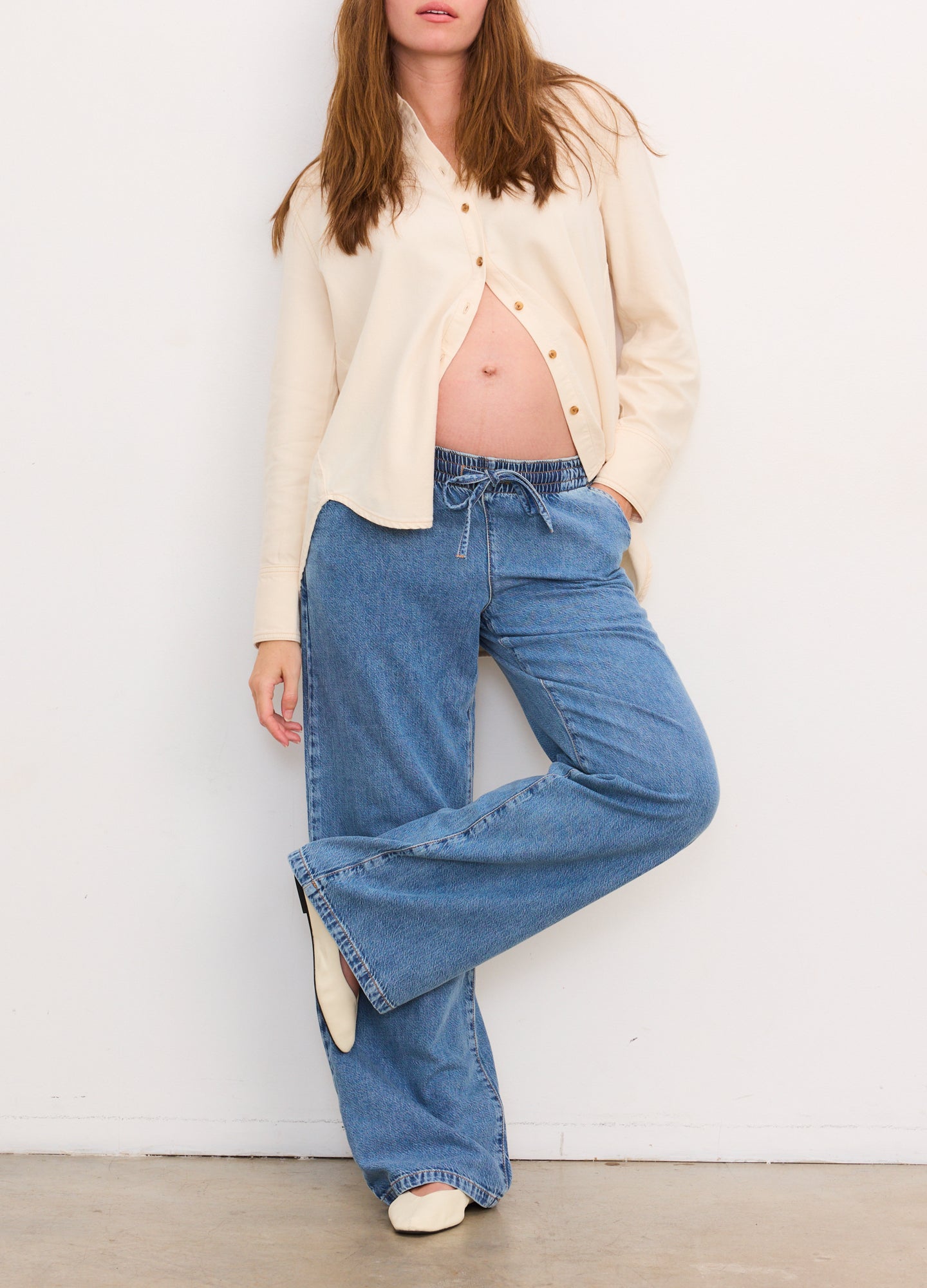Light blue wide-leg denim pants with a relaxed fit, designed for maternity wear, paired with a cream button-up cardigan.