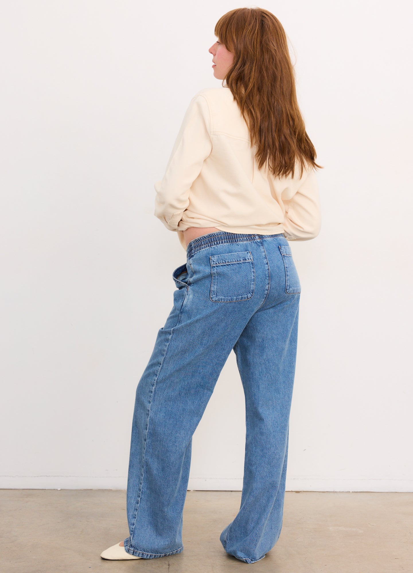 Blue wide-leg denim maternity pants with a high, stretchy waistband, modeled from the side.