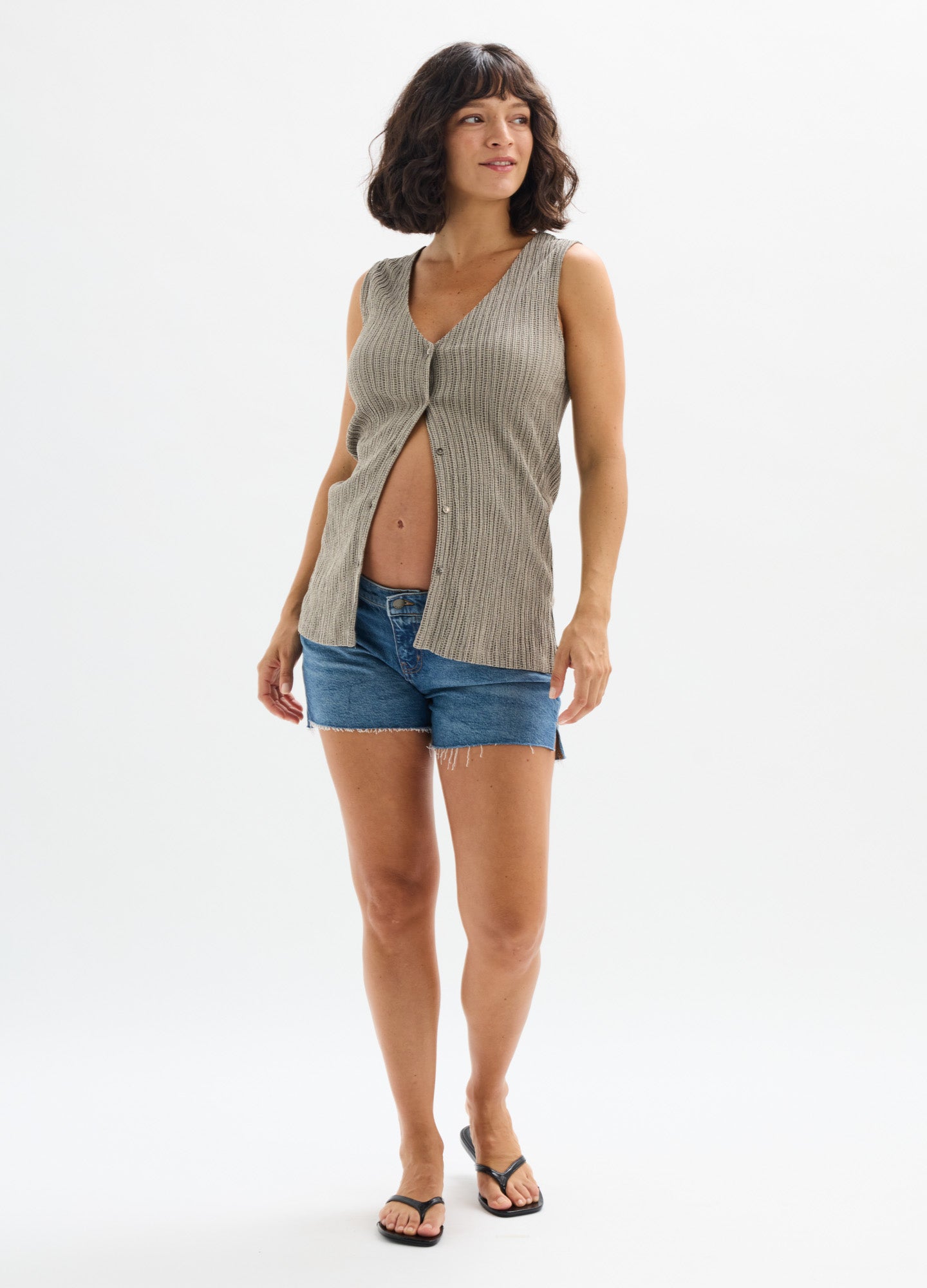 Sleeveless beige maternity tank with front buttons, paired with denim shorts and flip-flops.