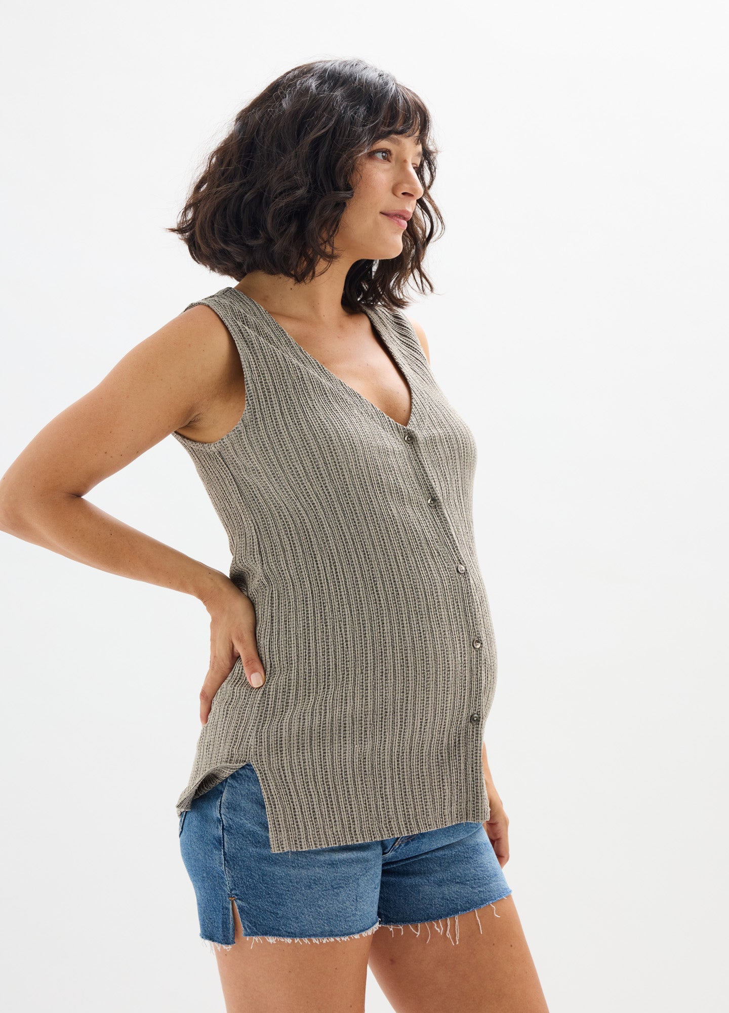 Sleeveless grey ribbed maternity tank top with side slits and V-neck, paired with denim shorts.