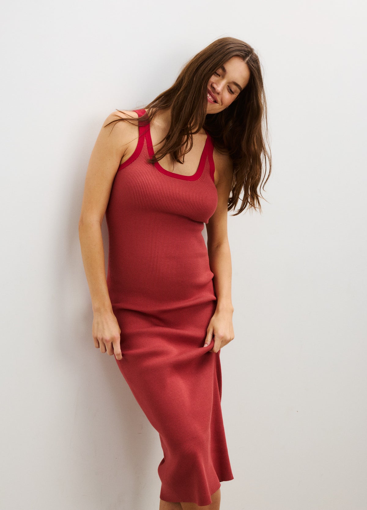 Sleeveless red maternity dress with a scoop neckline and a fitted silhouette designed for pregnant women.
