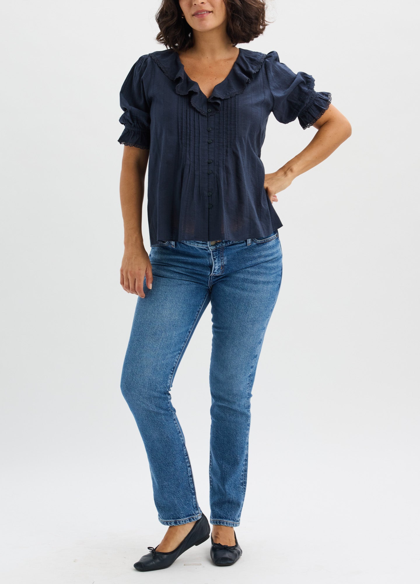 Navy blue maternity nursing blouse with ruffled collar and short puff sleeves, paired with blue jeans.