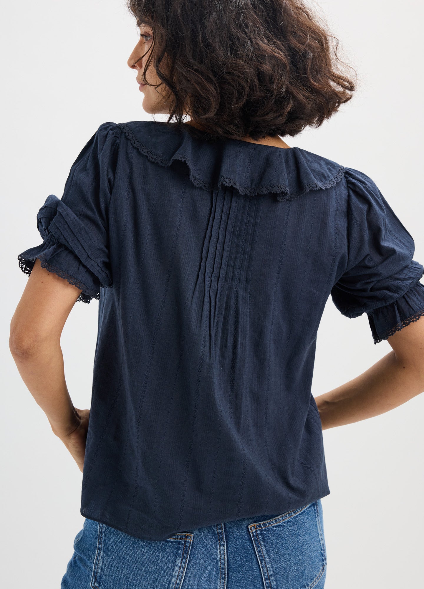 Navy maternity nursing blouse with ruffled collar, pintuck back detail, and rolled sleeves.