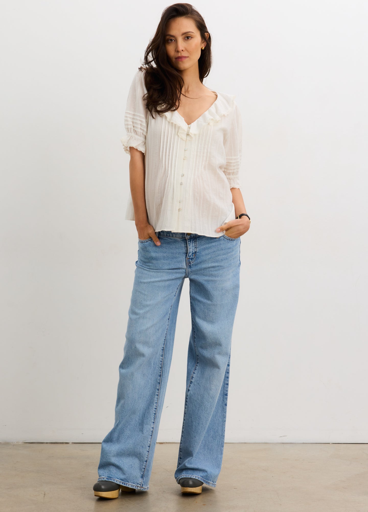 White short-sleeve nursing blouse with button front and relaxed fit, paired with light blue wide-leg jeans.