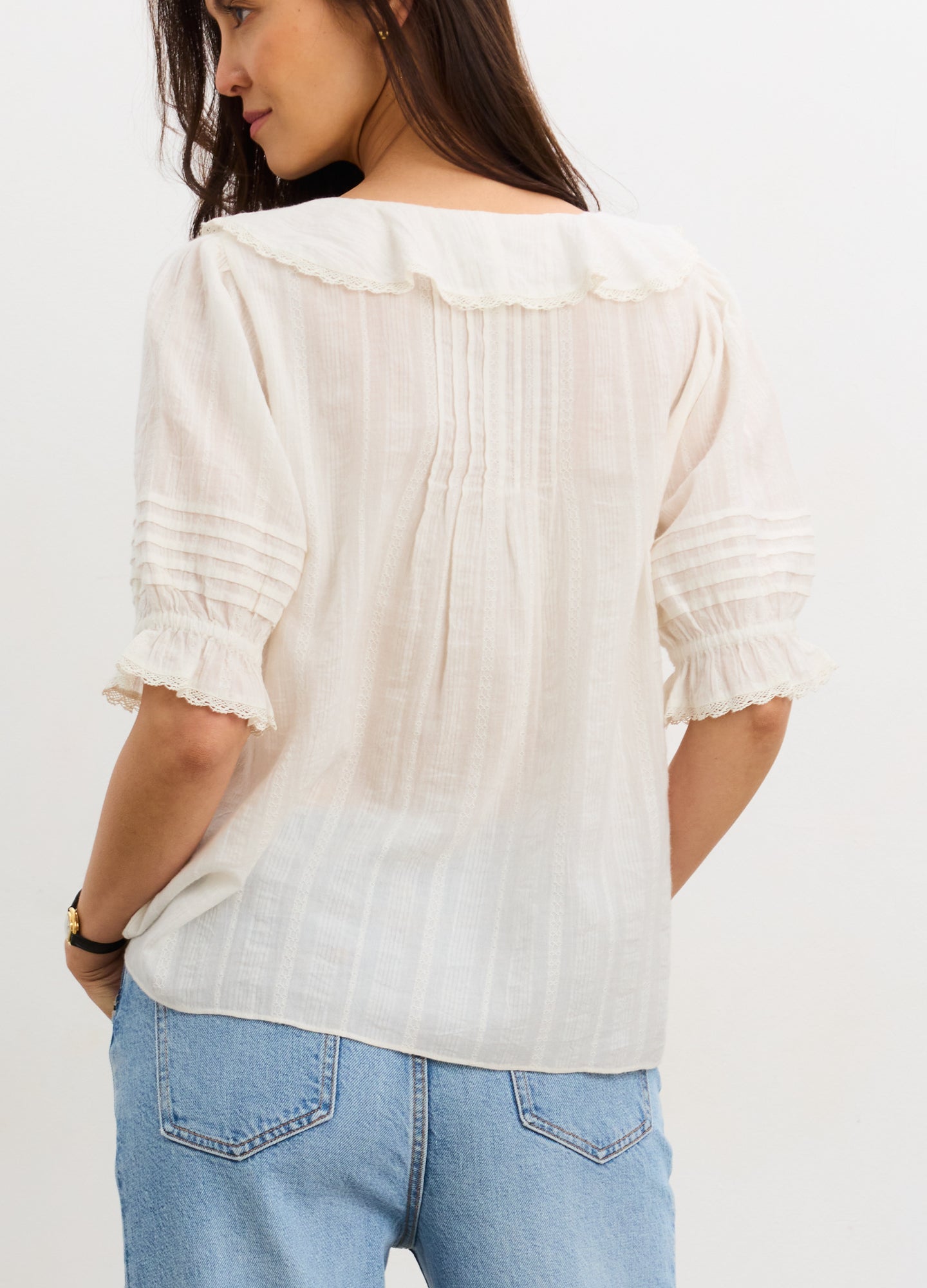 Cream-colored maternity nursing blouse with delicate pintuck detailing, ruffled collar, and elbow-length puff sleeves.