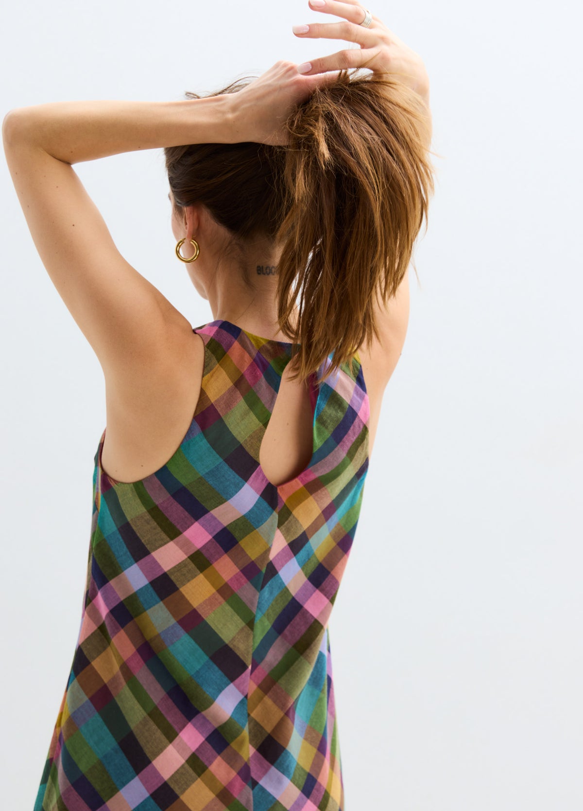 Sleeveless maternity mini dress with multicolor diagonal plaid and keyhole back detail.