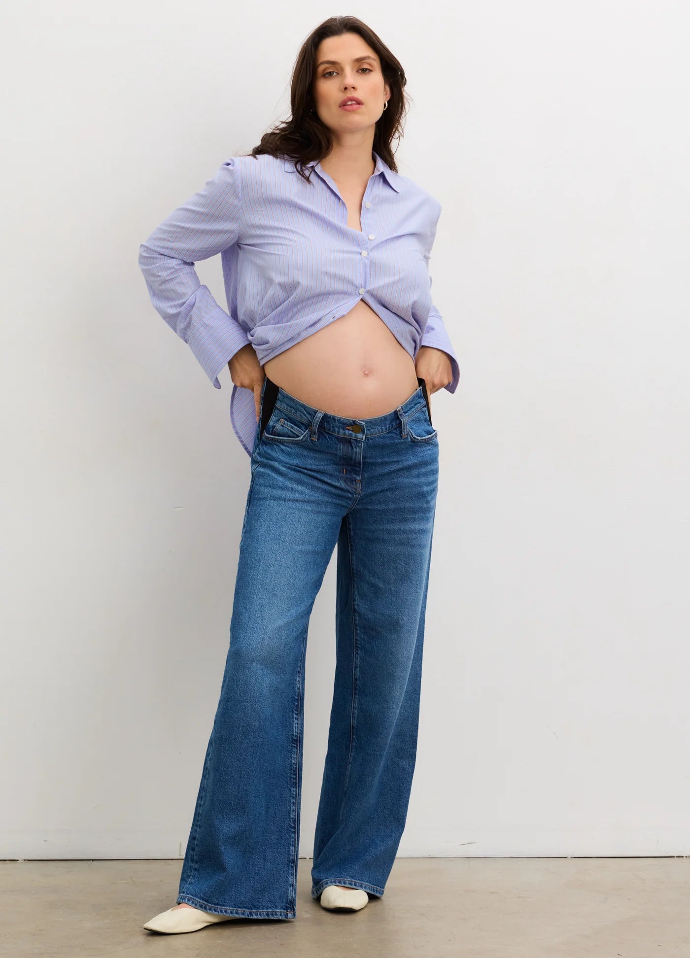 Pregnant woman wearing true indigo wide-leg maternity jeans with a relaxed fit and belly panel.
