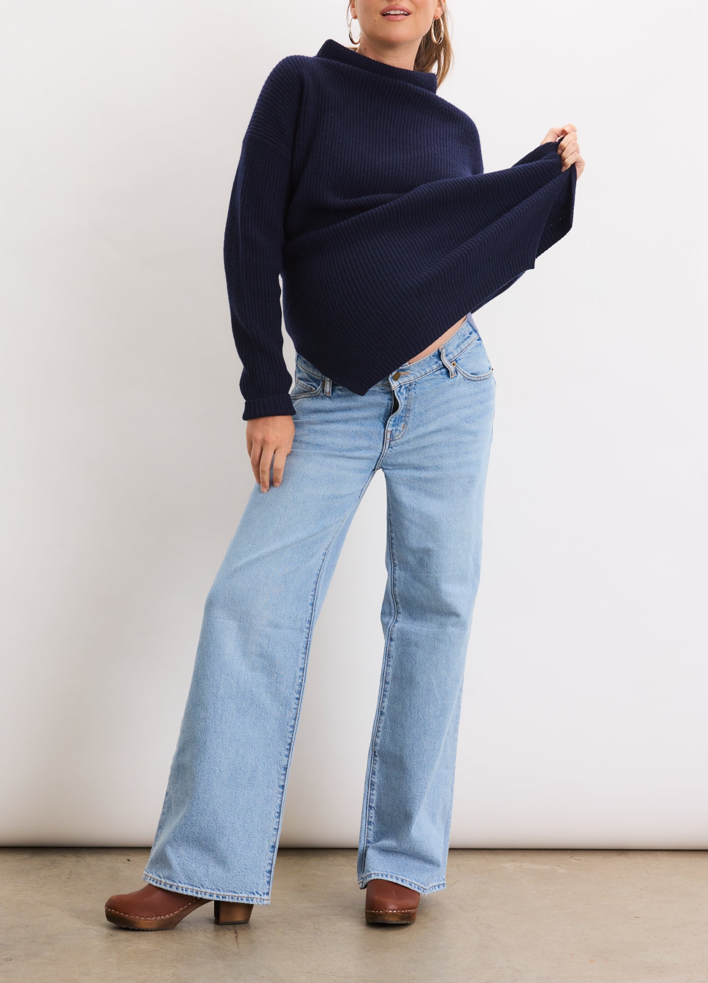 Light blue wide-leg maternity jeans with relaxed fit and stretchy waistband, styled with navy sweater and brown shoes.