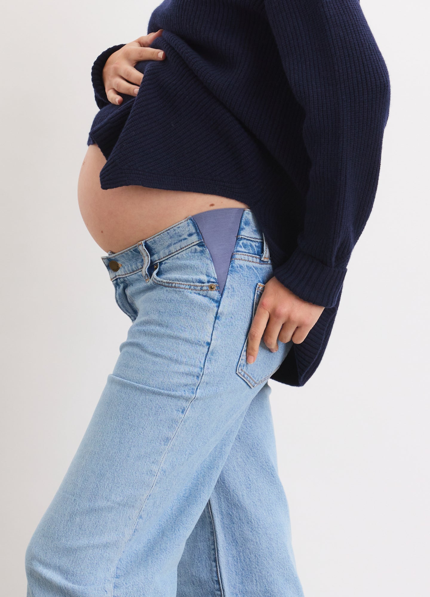 Light wash relaxed wide leg maternity jeans with stretchy side panels, worn by pregnant woman.