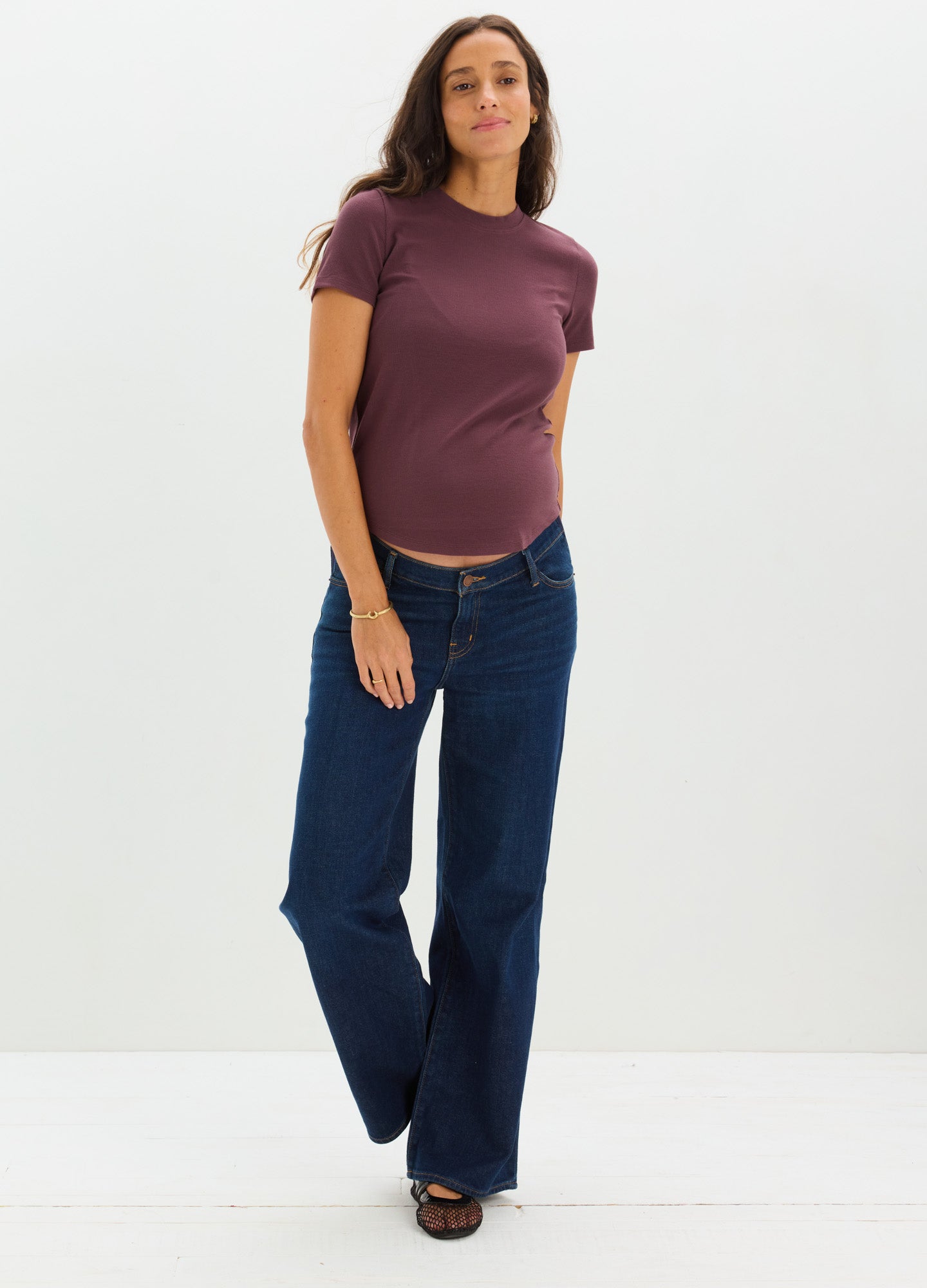 Dark blue wide-leg maternity jeans with a stretchy waistband worn by pregnant woman in a purple t-shirt.
