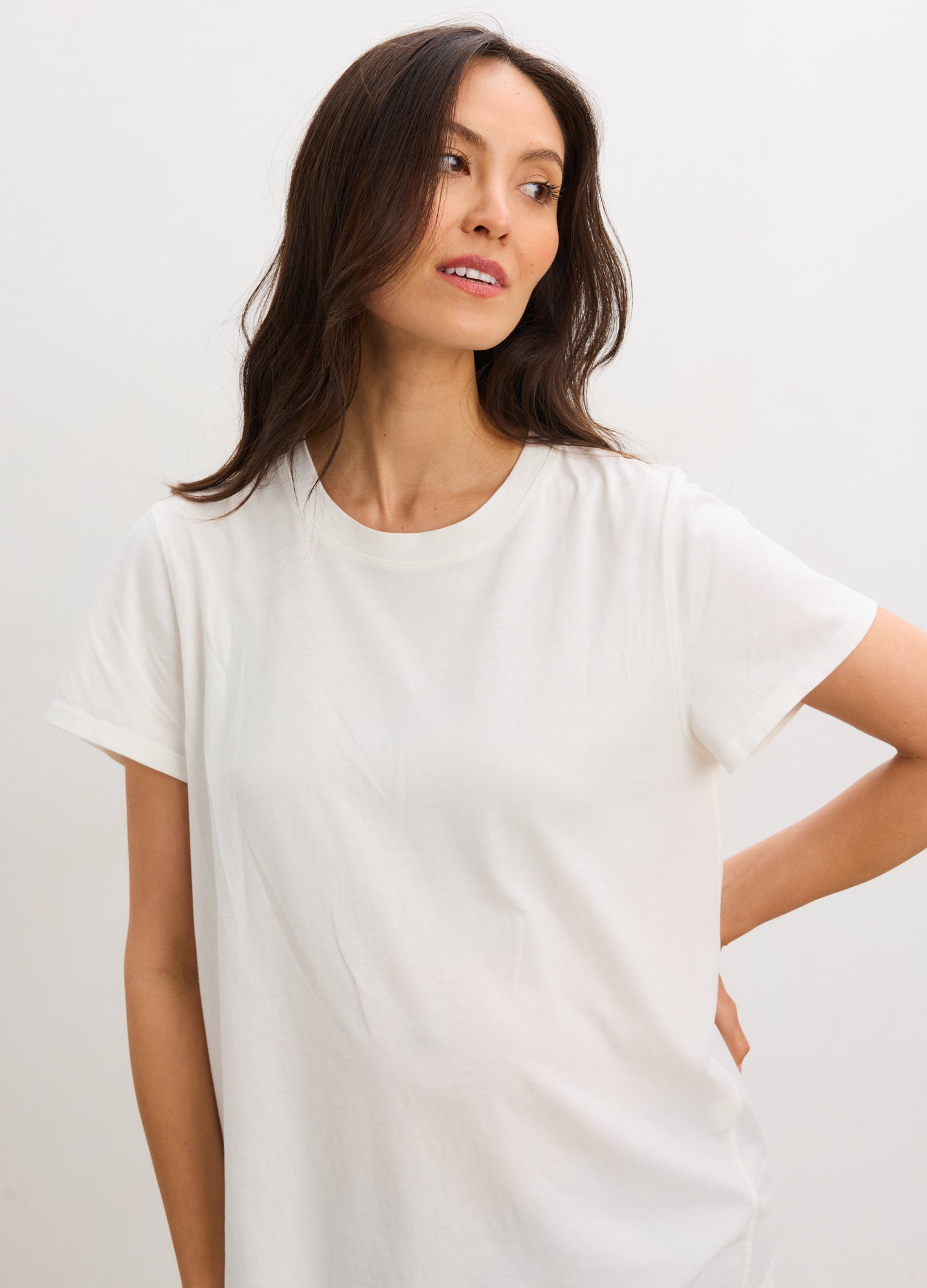 White washed cotton crew neck maternity t-shirt with short sleeves, worn by a pregnant woman.