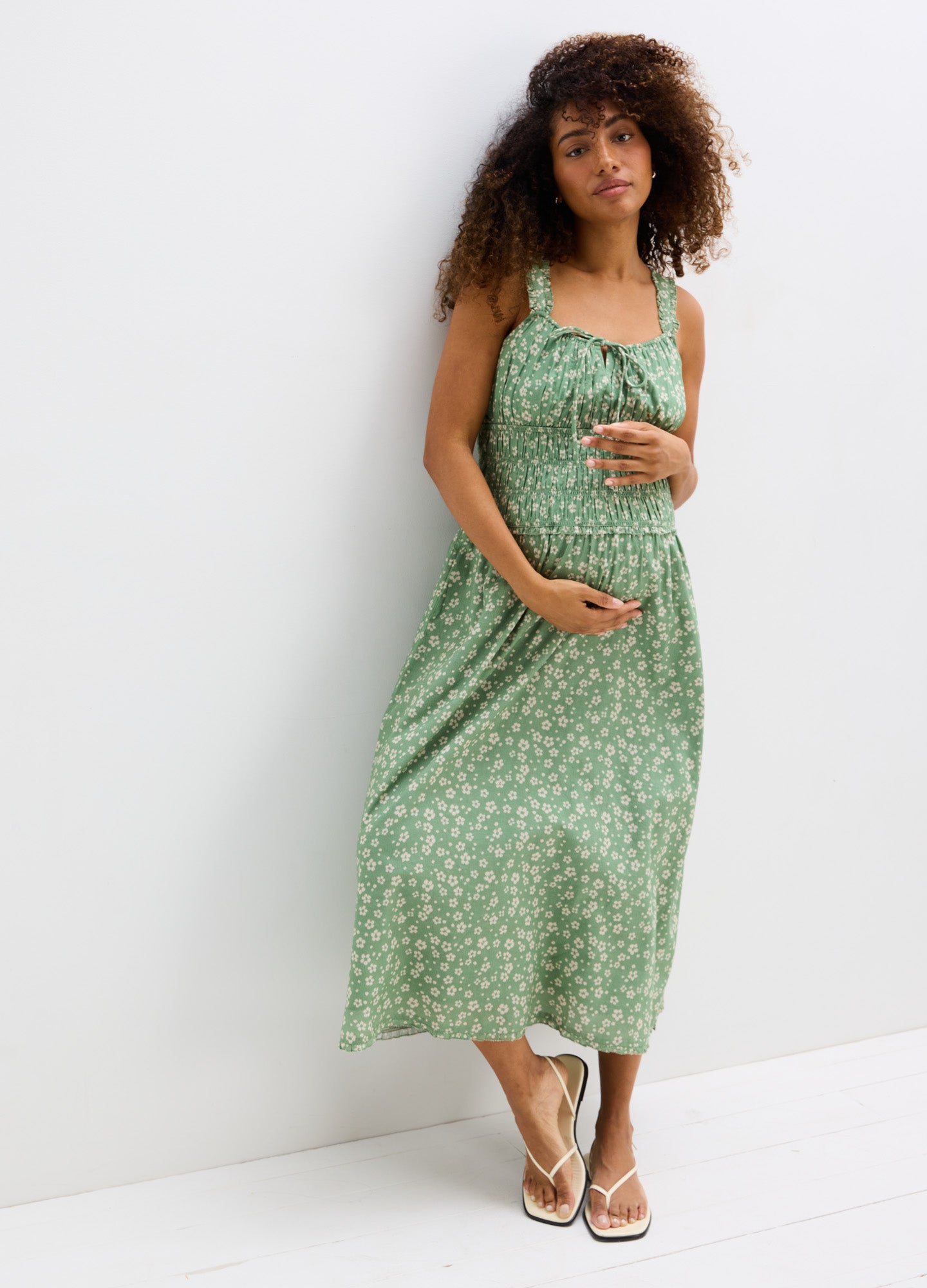 Green floral maternity dress with smocked bodice, square neckline, and flowy midi skirt.