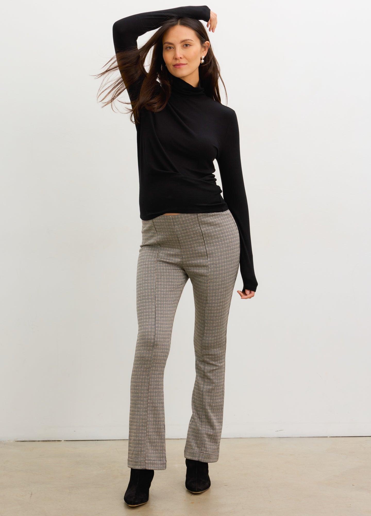 Pregnant woman wearing mini houndstooth maternity seamed stretch crop pants with black turtleneck and boots.