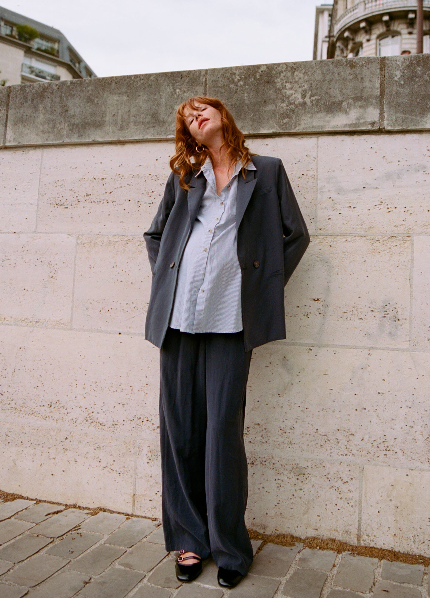 Pregnant woman wearing slate blue maternity pull-on trousers with a relaxed fit and a matching tailored blazer.