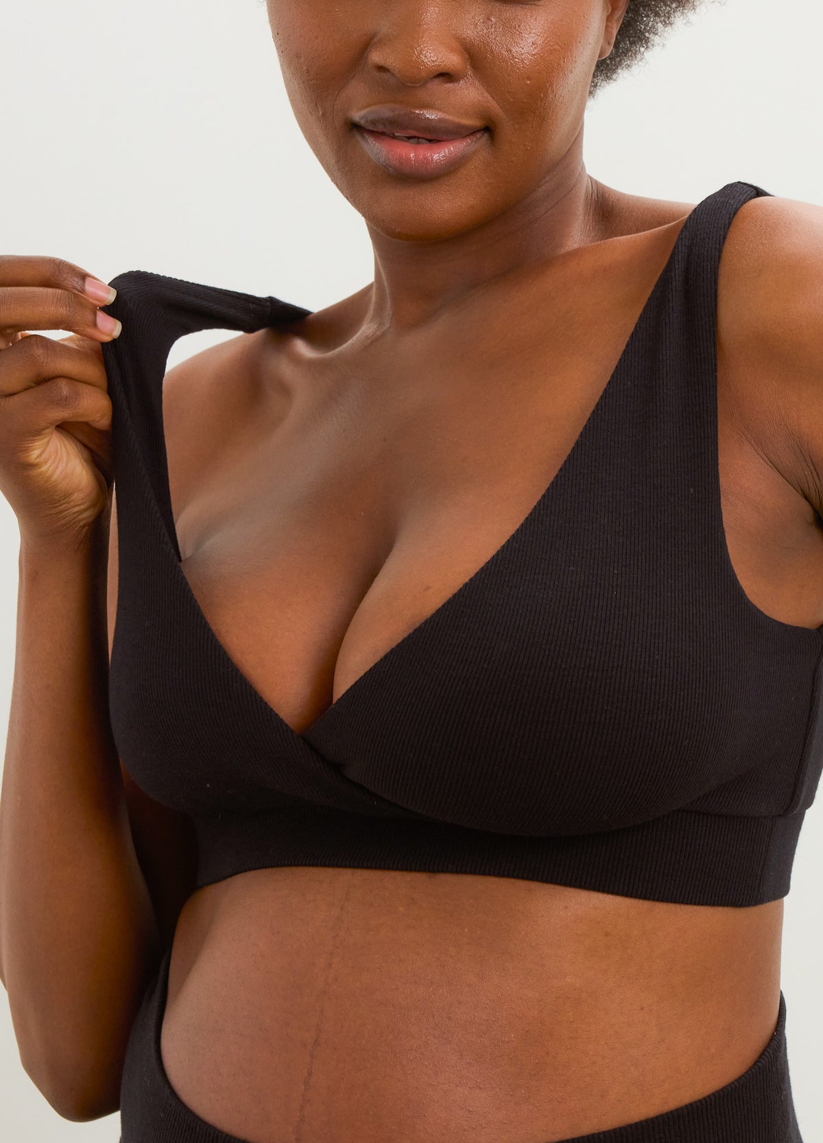 Black ribbed maternity nursing bra with a soft wrap-front neckline and wide shoulder straps.