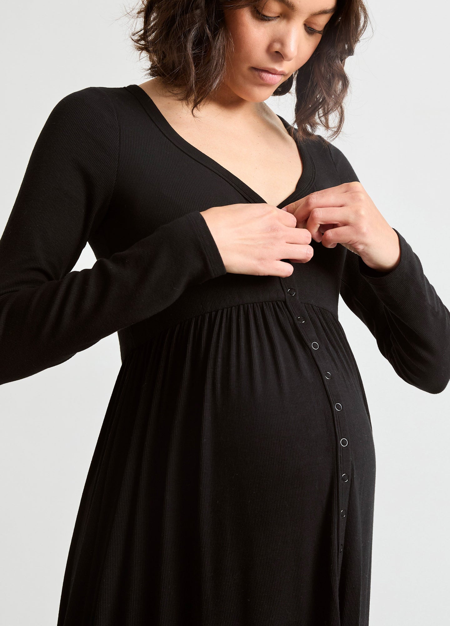 Black ribbed maternity nursing dress with long sleeves and button-front detail on pregnant model.
