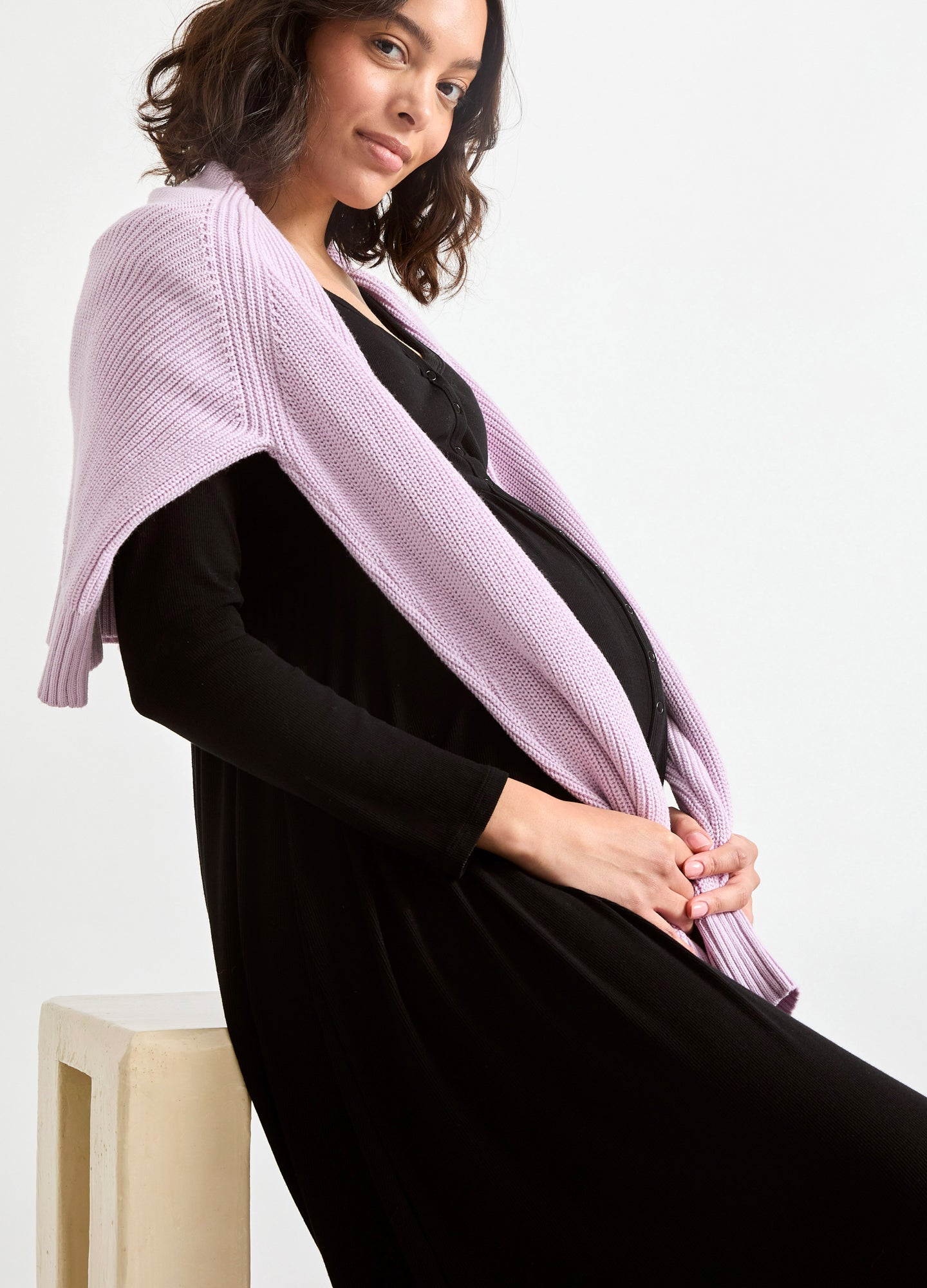 Black long rib-knit nursing dress with fitted silhouette and long sleeves, styled with a soft lilac knit draped over.