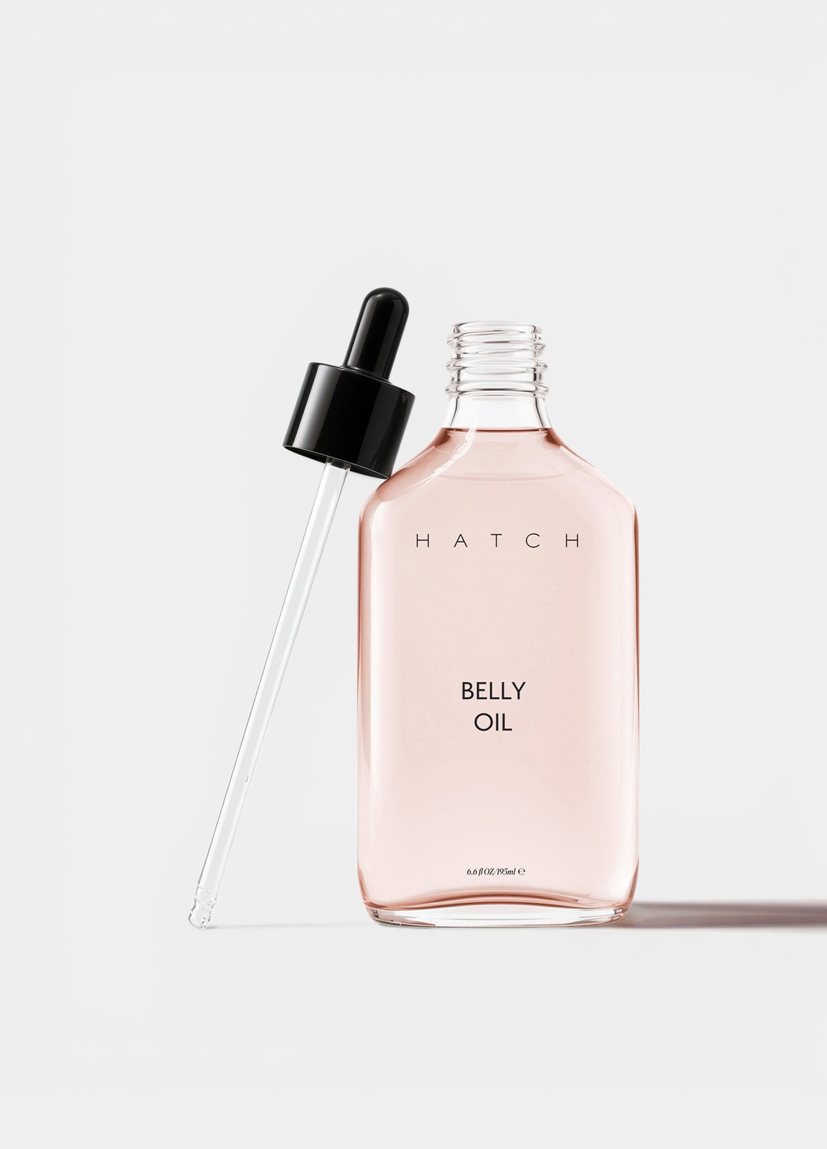 Clear rectangular glass bottle with pale pink belly oil and black dropper cap.
