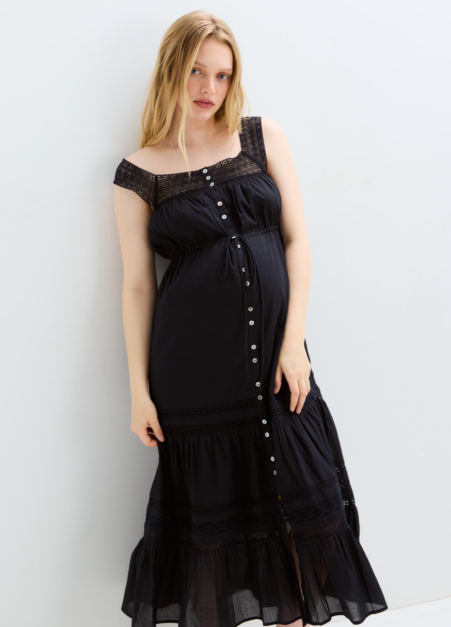 Black off-shoulder maternity dress with button-down front and tiered hem, flowy fabric.