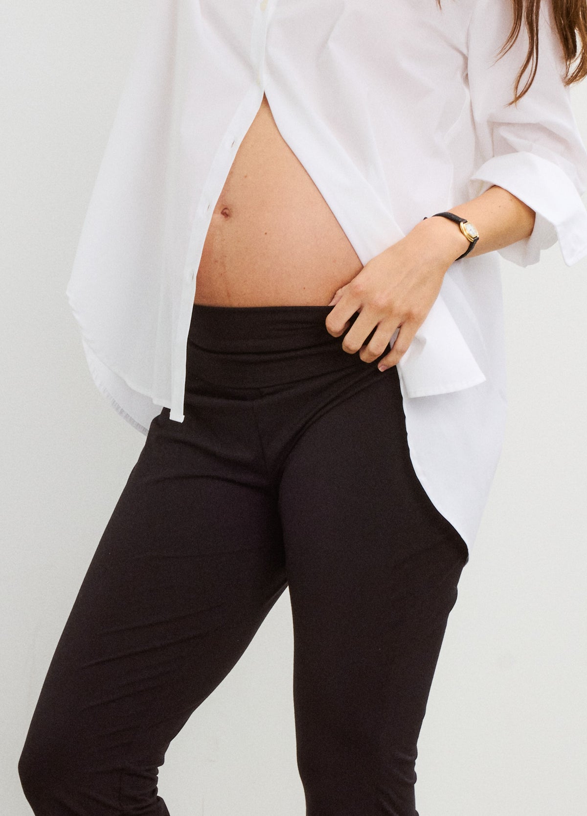 Black maternity crop flare leggings with high stretchy waistband, styled with white button-up shirt.