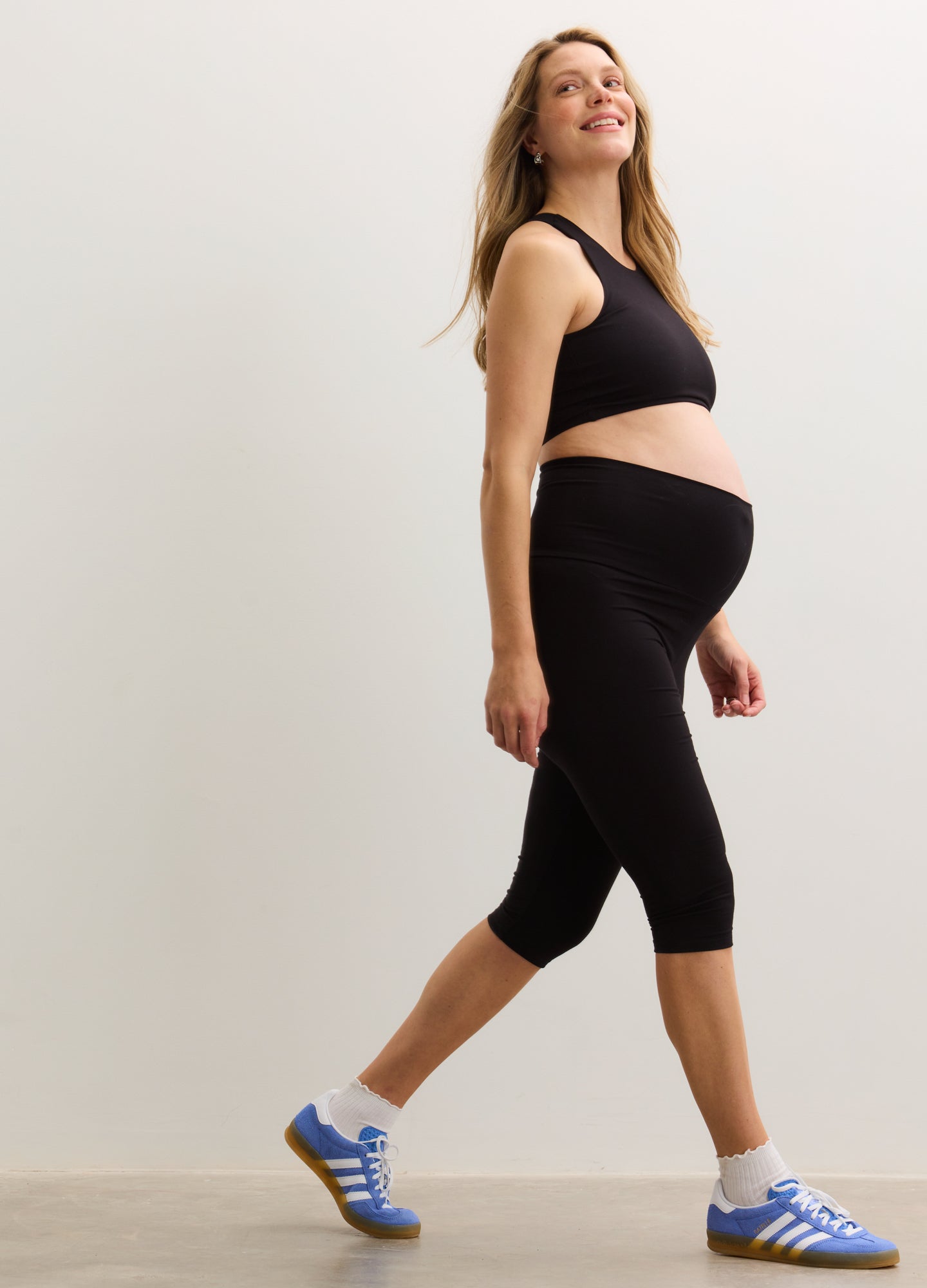 Black stretchy capri leggings designed for maternity with high waistband supporting pregnant belly.