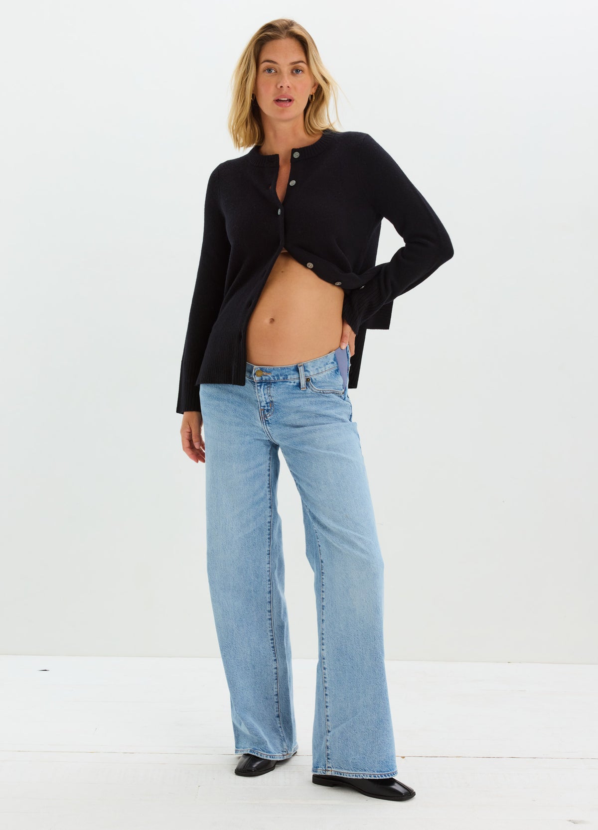 Black cropped knit cardigan with long sleeves styled open over jeans on pregnant model.