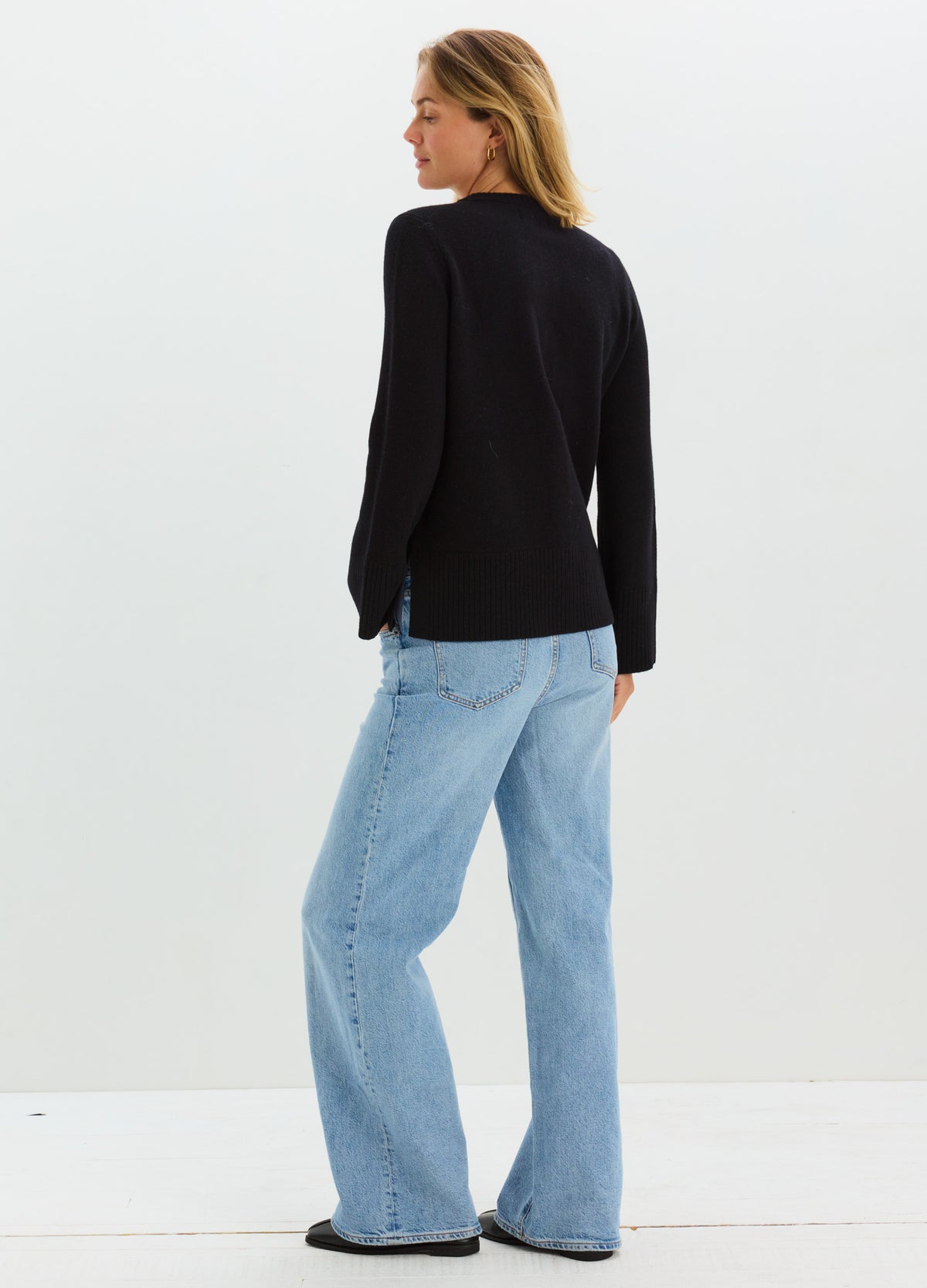 Black long-sleeve maternity cardigan with relaxed fit, worn over light blue loose jeans on pregnant model.