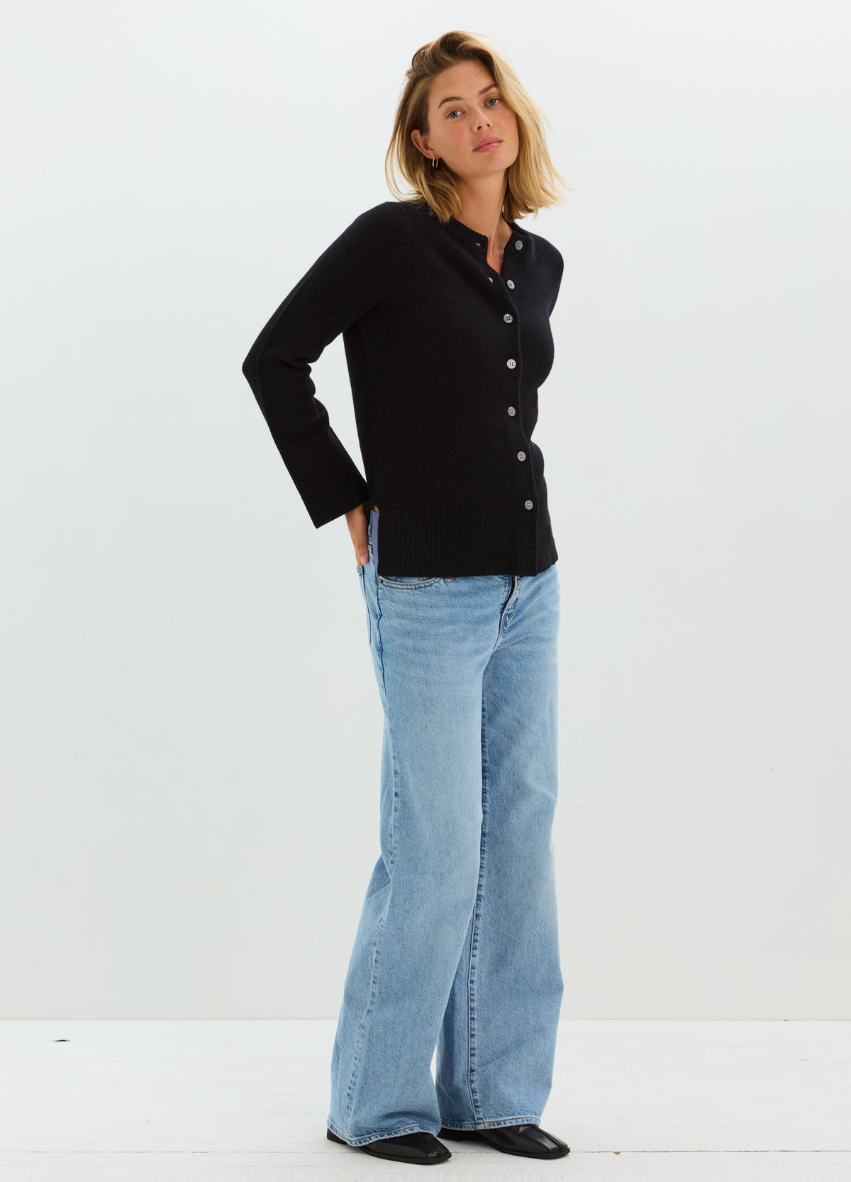 Black fitted maternity cardigan with buttons, long sleeves, worn with light blue flared jeans.