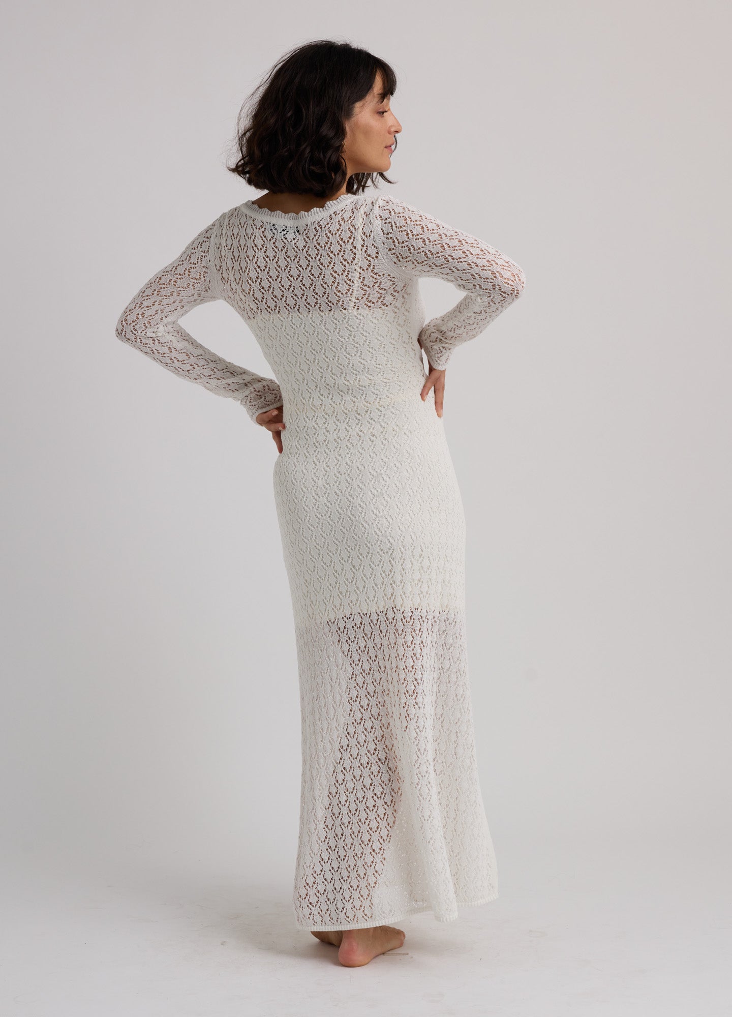 White semi-sheer knit maternity maxi dress with long sleeves and fitted silhouette.