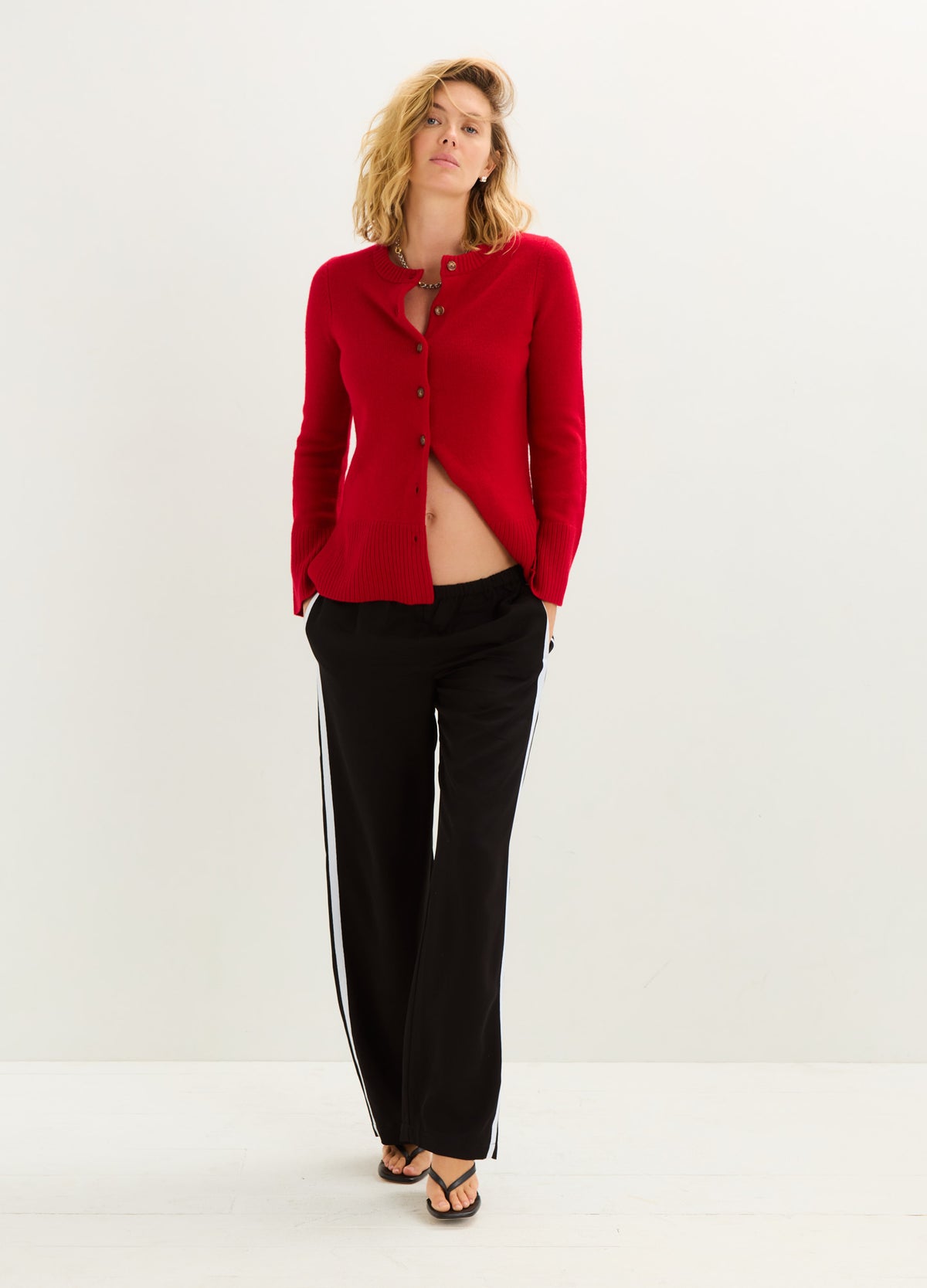 Bright red button-front cardigan with a soft knit texture, paired with black trousers.