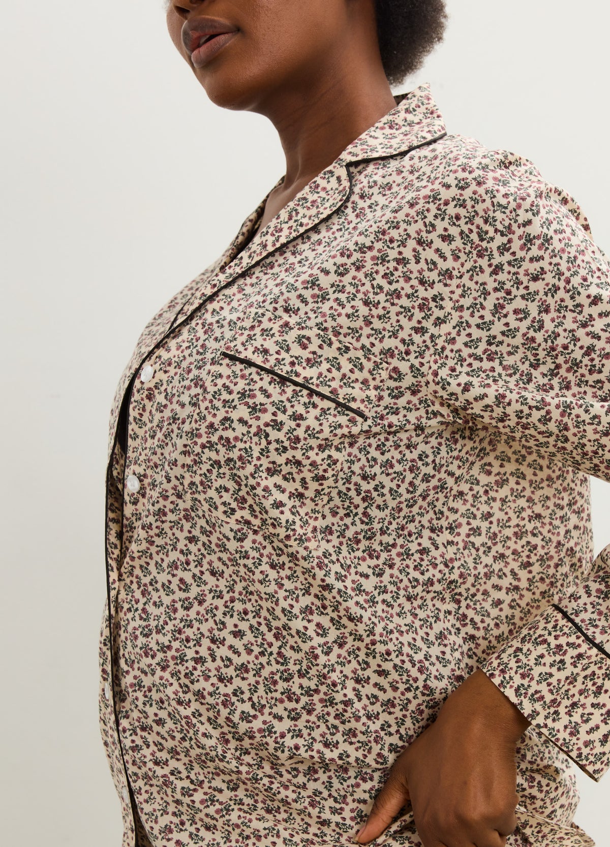 Pregnant model wearing cream cotton maternity pajamas with a tiny floral print and dark piping.