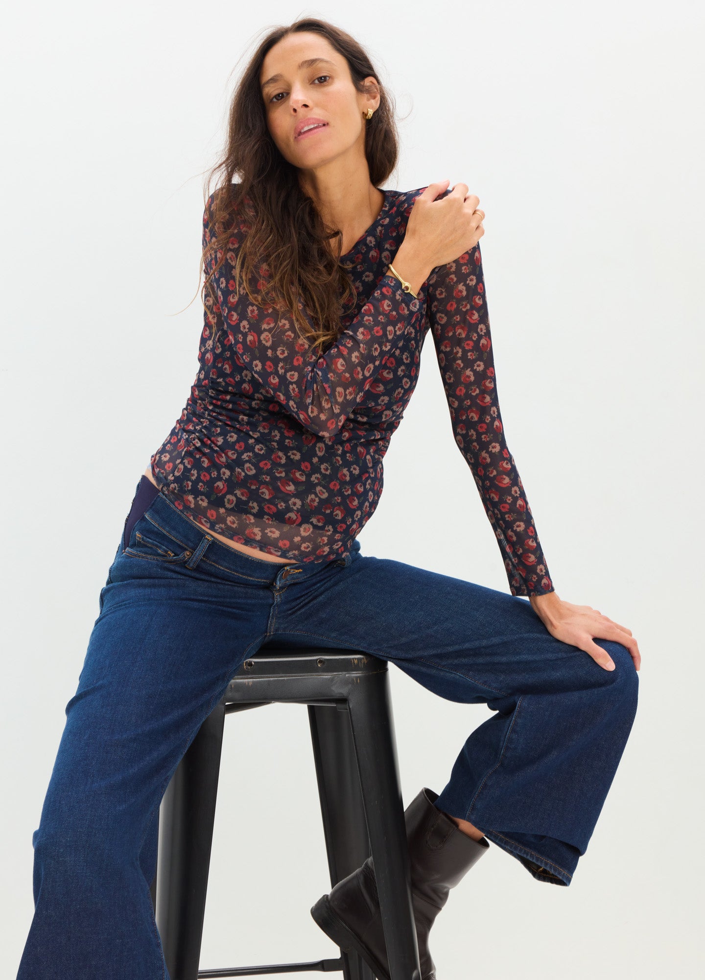 Navy long-sleeve maternity top with red floral print, fitted silhouette, worn with wide-leg jeans and boots.
