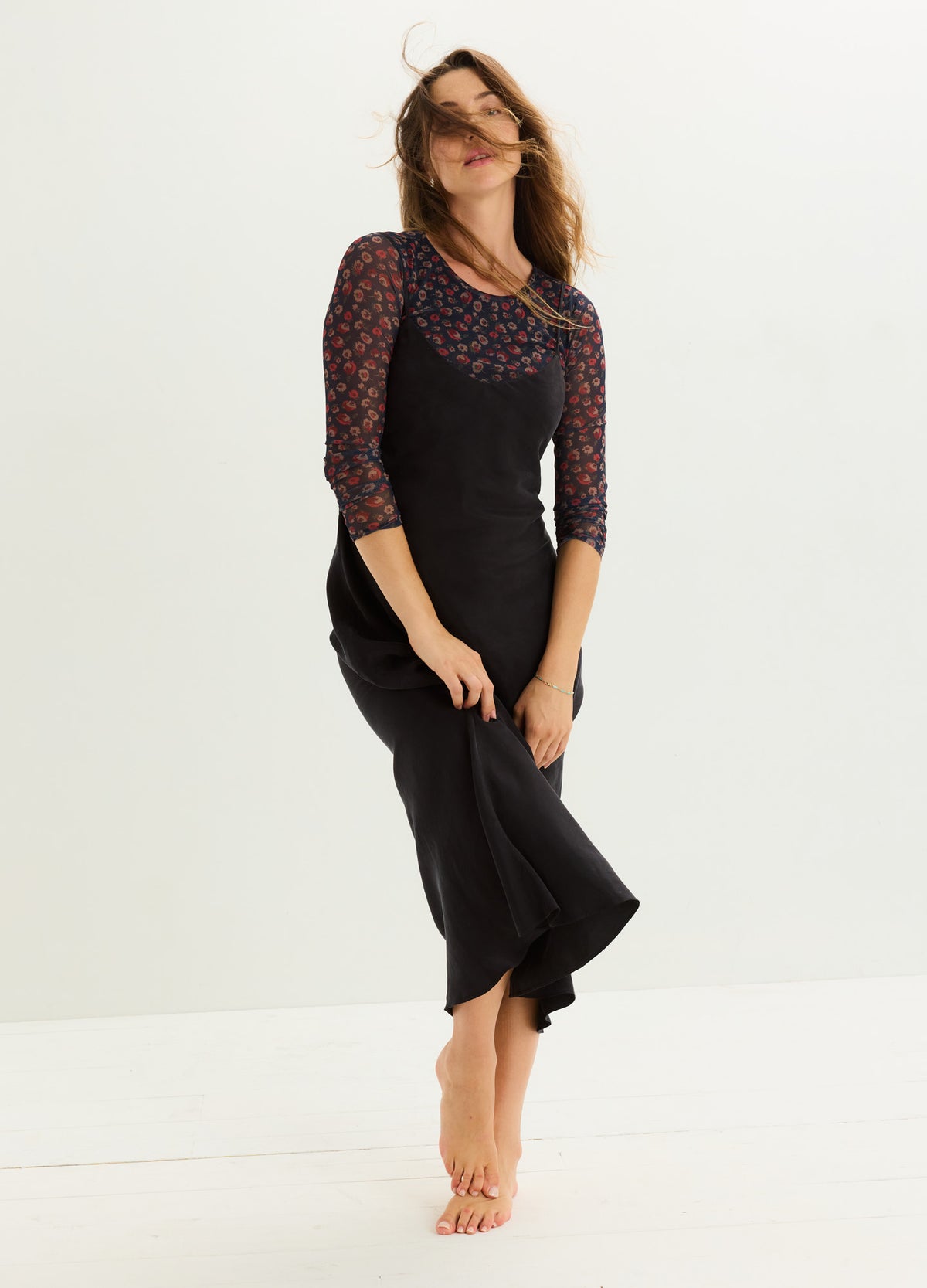Black sleeveless maternity dress layered over floral 3/4 sleeve top, flowing skirt hem.