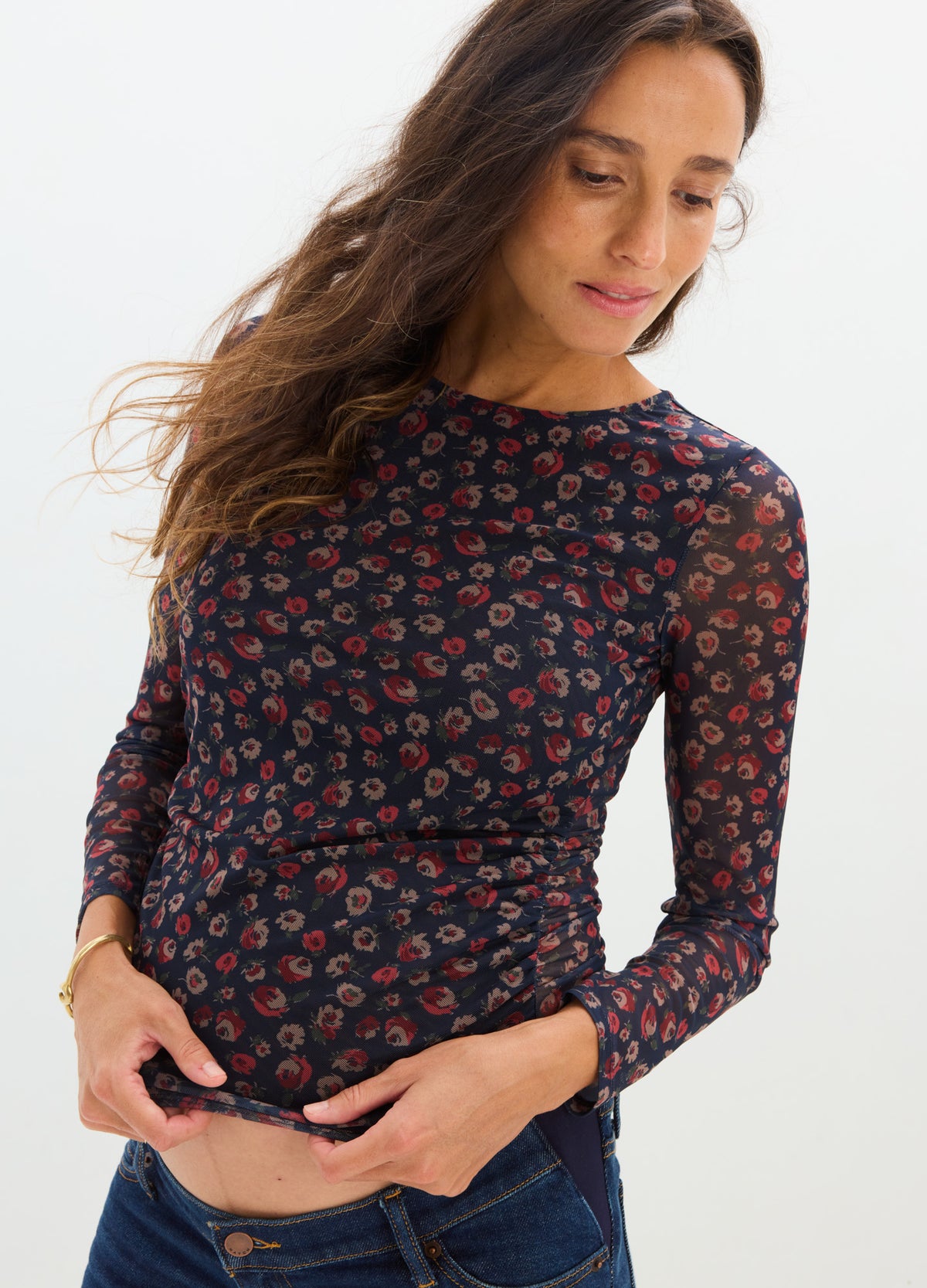 Black long-sleeve maternity top with red floral pattern, fitted around pregnant belly.
