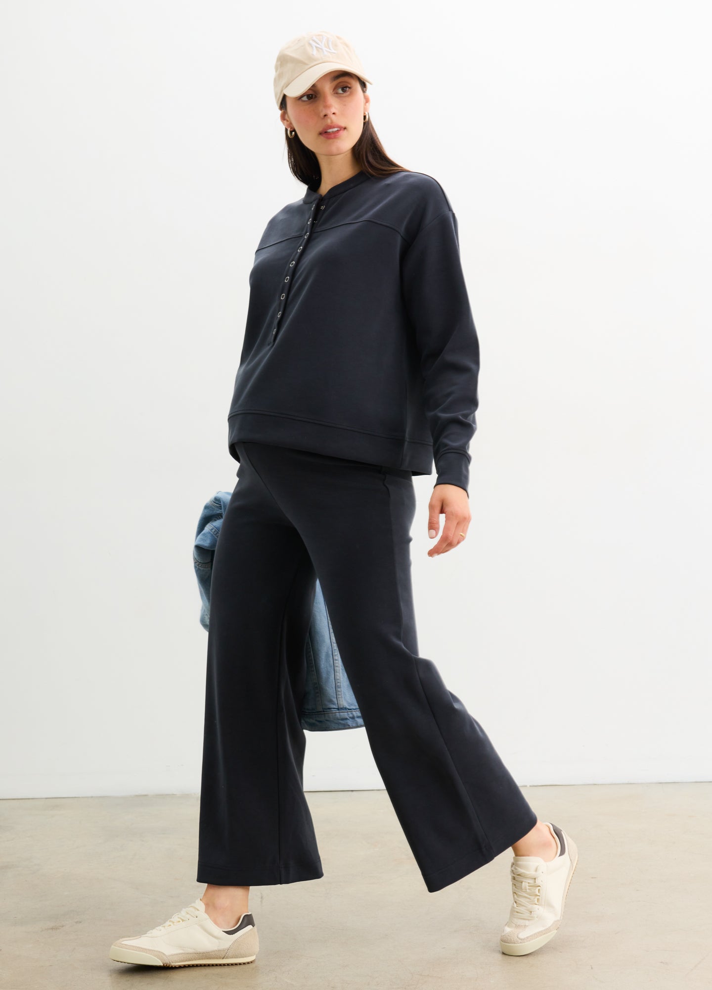 Black wide-leg maternity pants with a relaxed fit, paired with a matching black zip-up jacket and white sneakers.