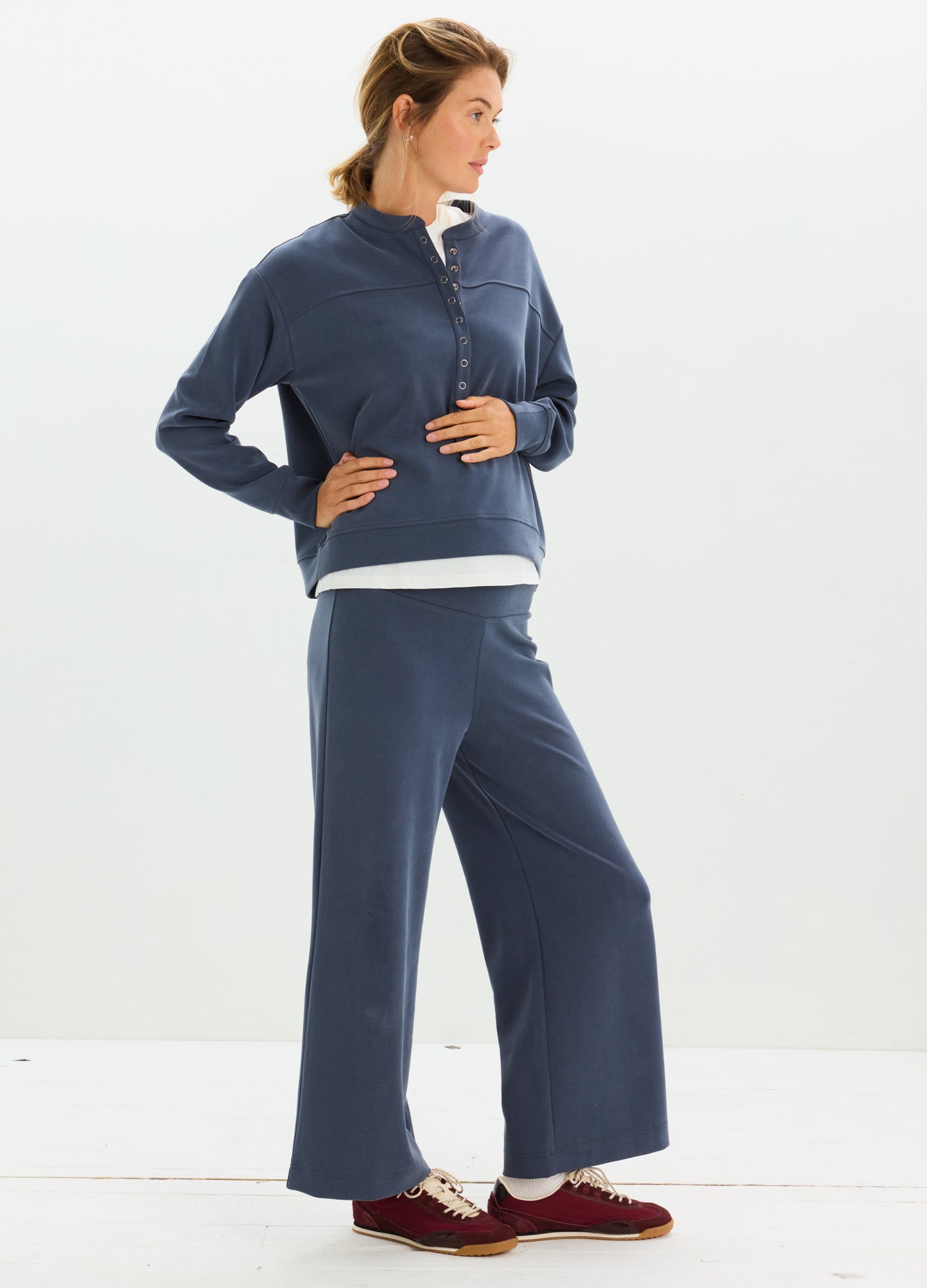 Navy blue maternity lounge pants with wide legs paired with matching long-sleeve top and burgundy slippers.