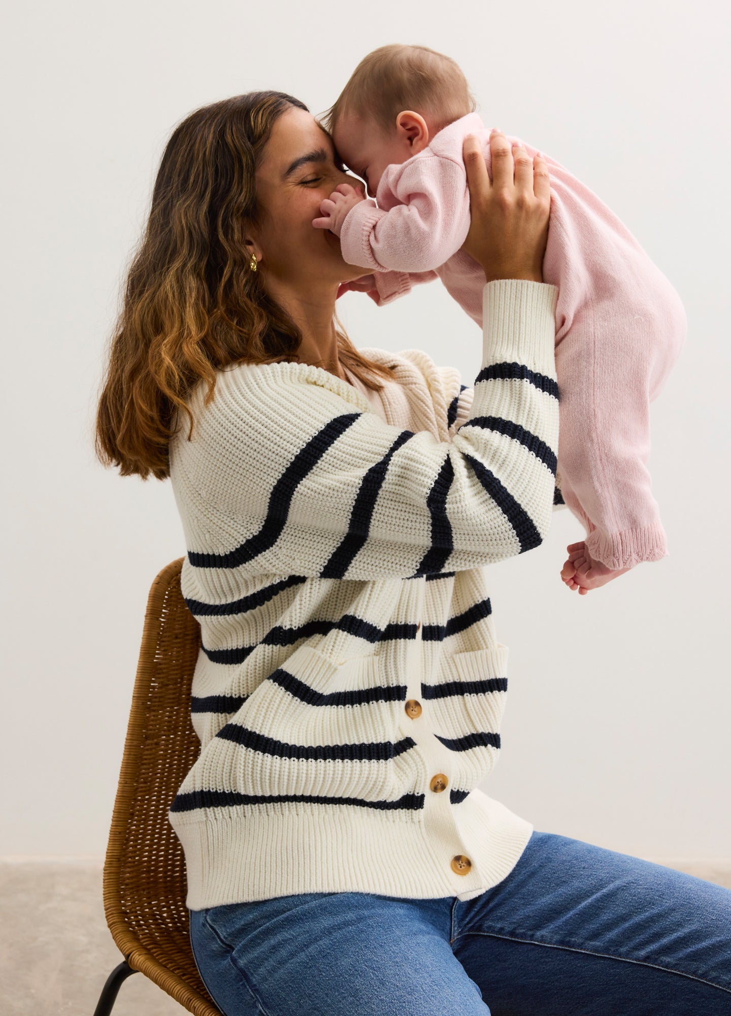 Cream cotton cardigan with navy stripes and brown buttons, worn by pregnant woman holding a baby.
