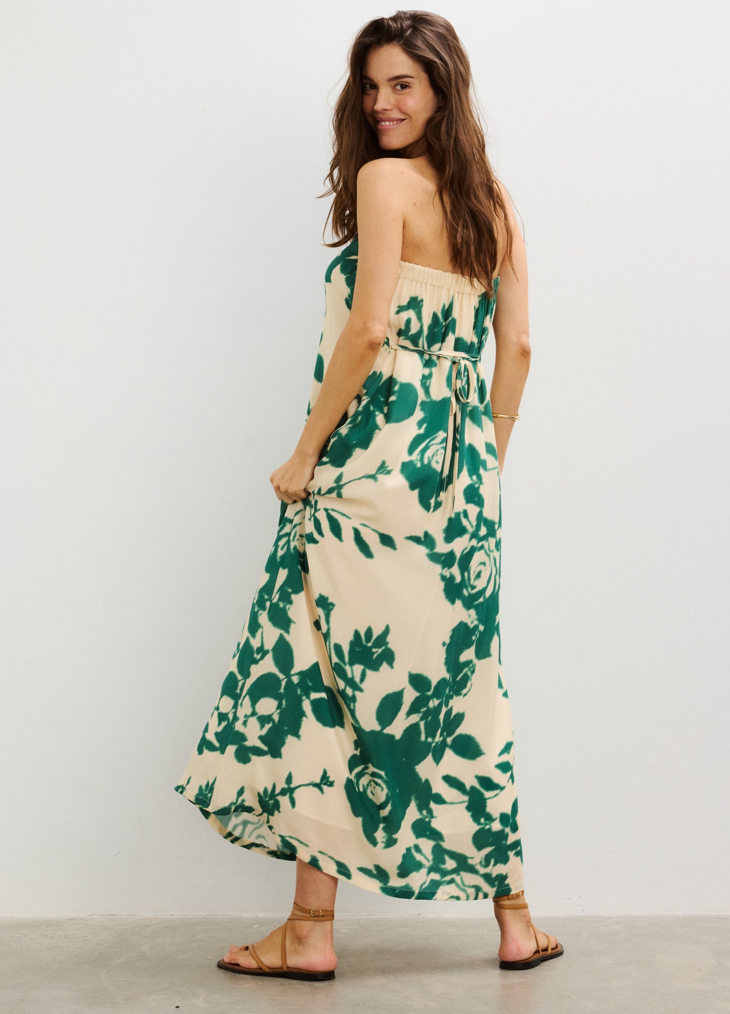 Cream strapless maternity dress with green floral print, fitted bust, and flowing skirt.