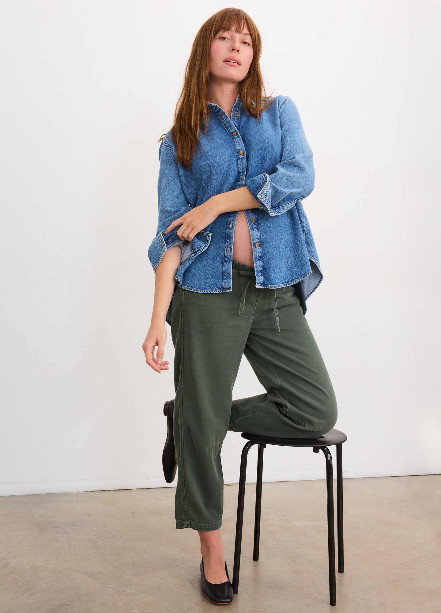 Light blue denim boyfriend shirt with loose fit and rolled-up sleeves on pregnant model.