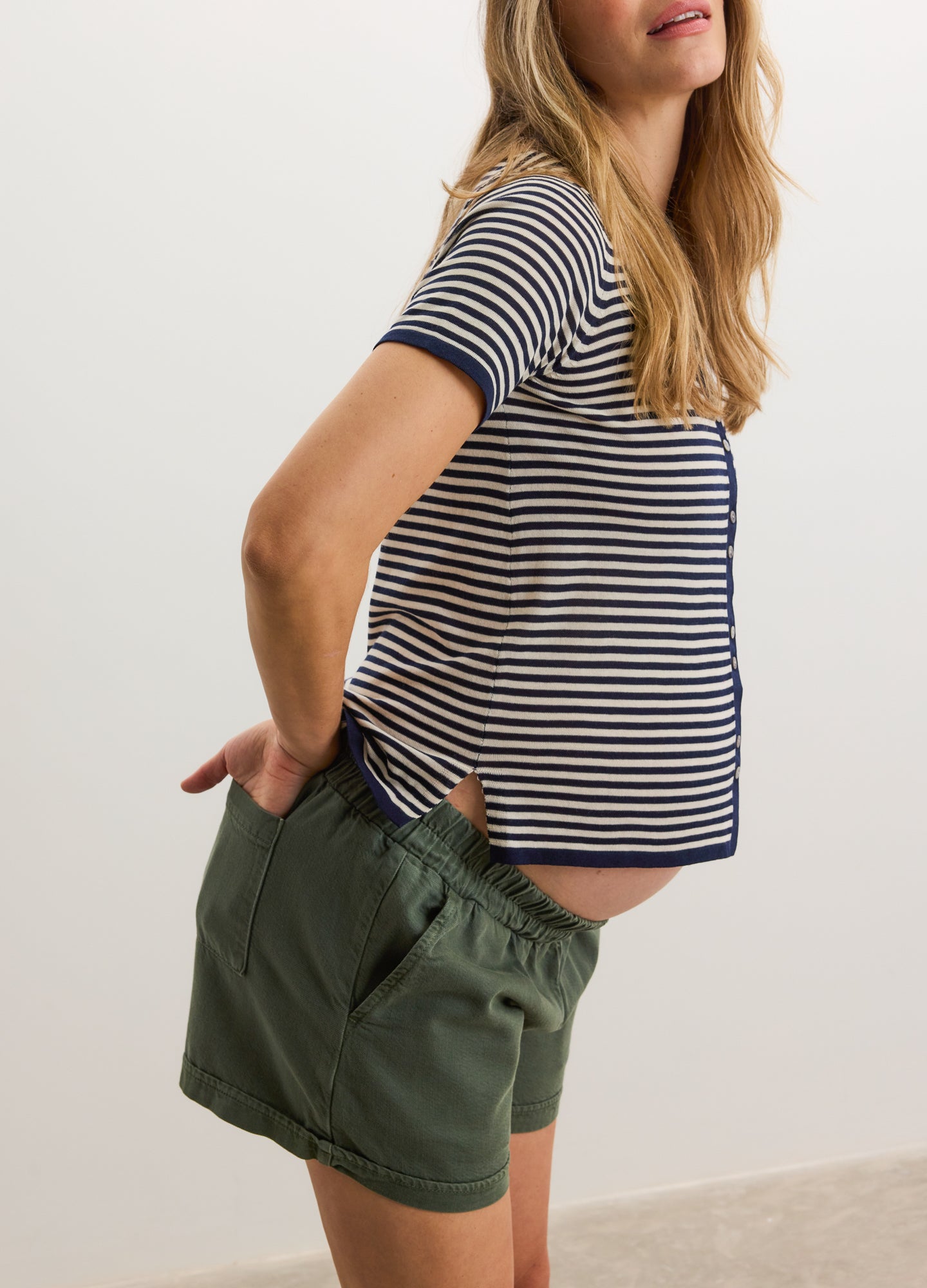 Olive green loose-fit maternity shorts with elastic waistband paired with navy and white striped short-sleeve top.
