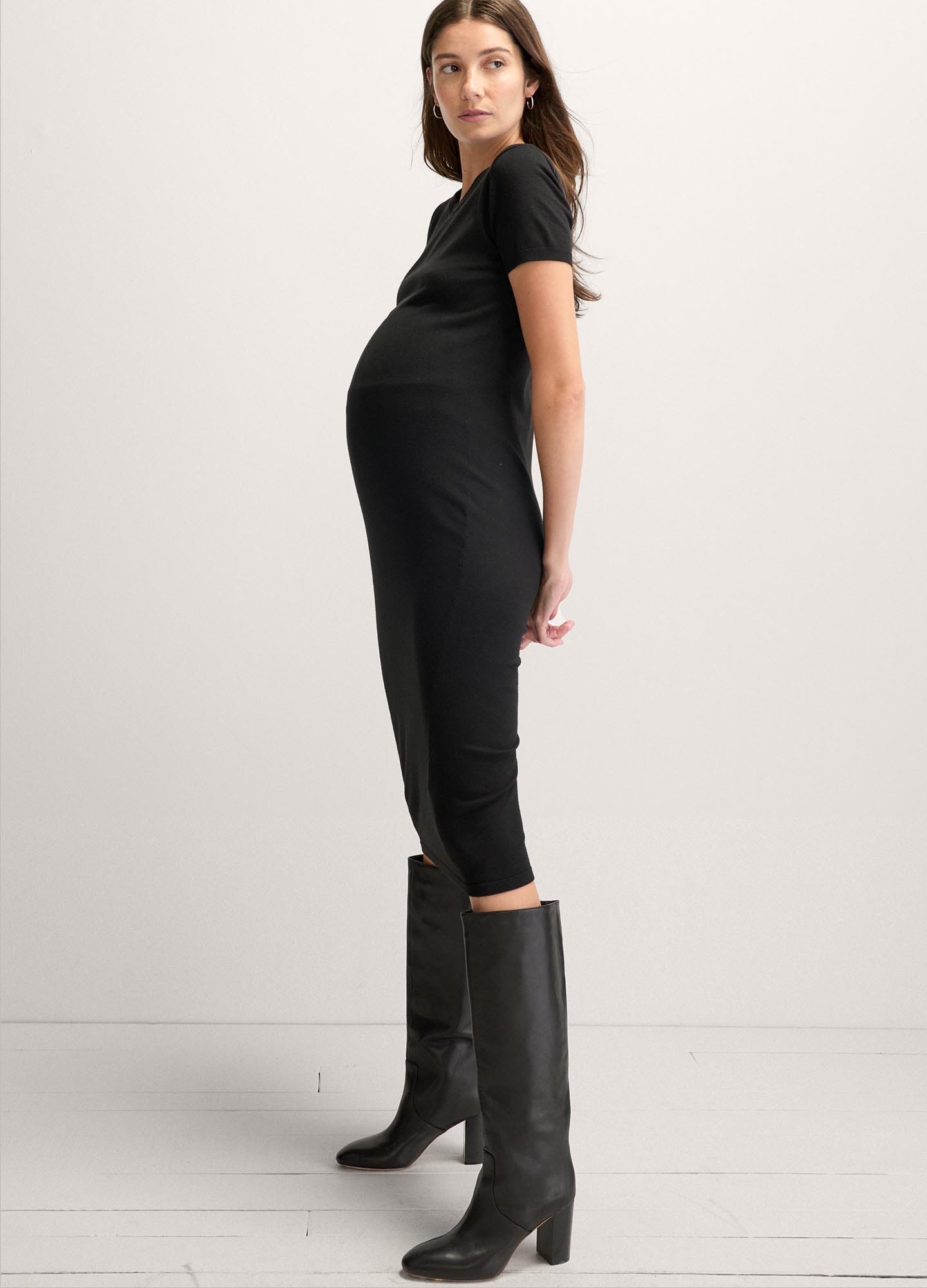 The Eliza Dress POS - Black short-sleeve maternity dress with nursing-friendly design and fitted silhouette, styled with tall black boots.