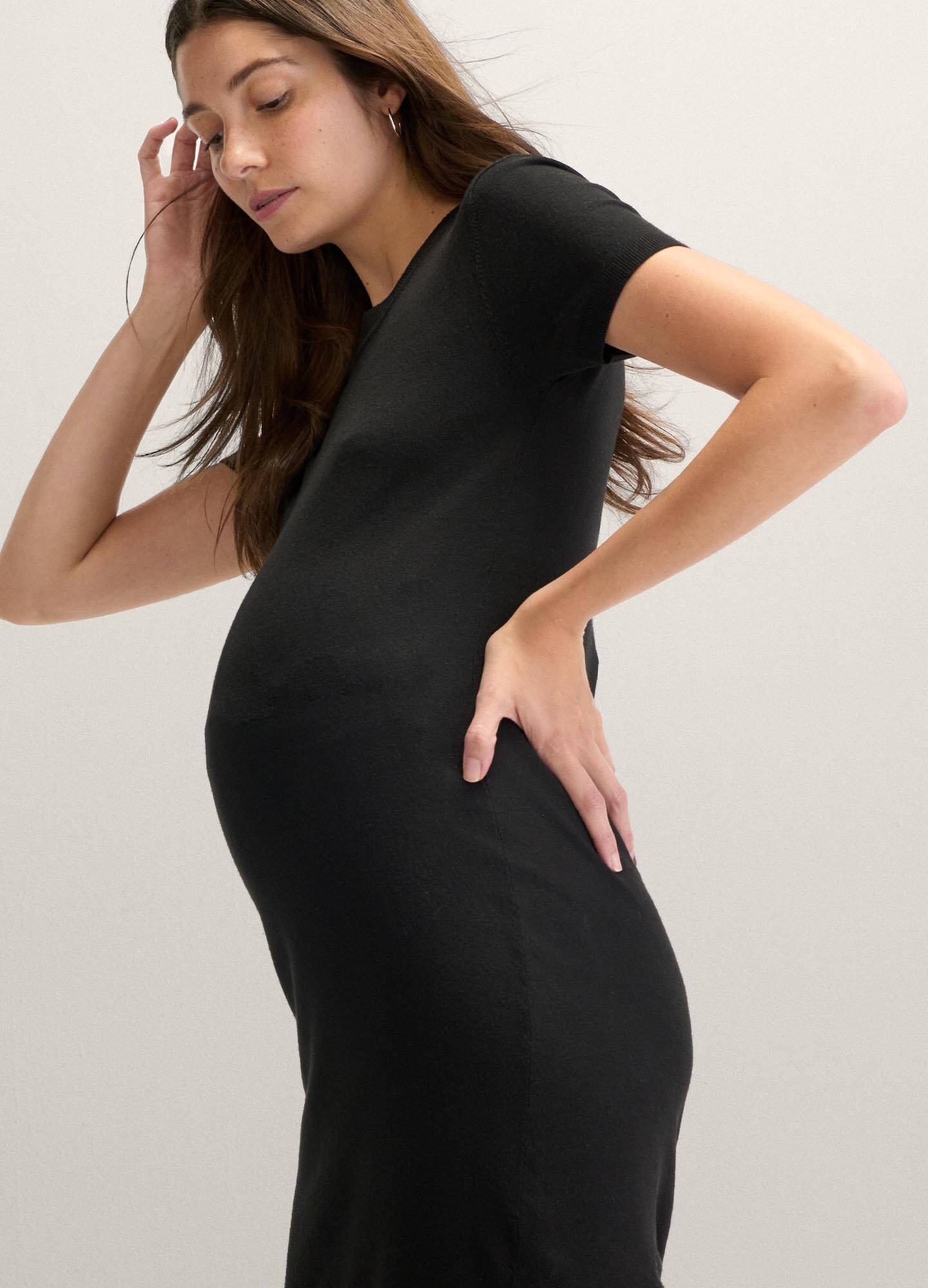 The Eliza Dress POS - Black short-sleeve maternity dress with nursing-friendly design and fitted silhouette, styled with tall black boots.