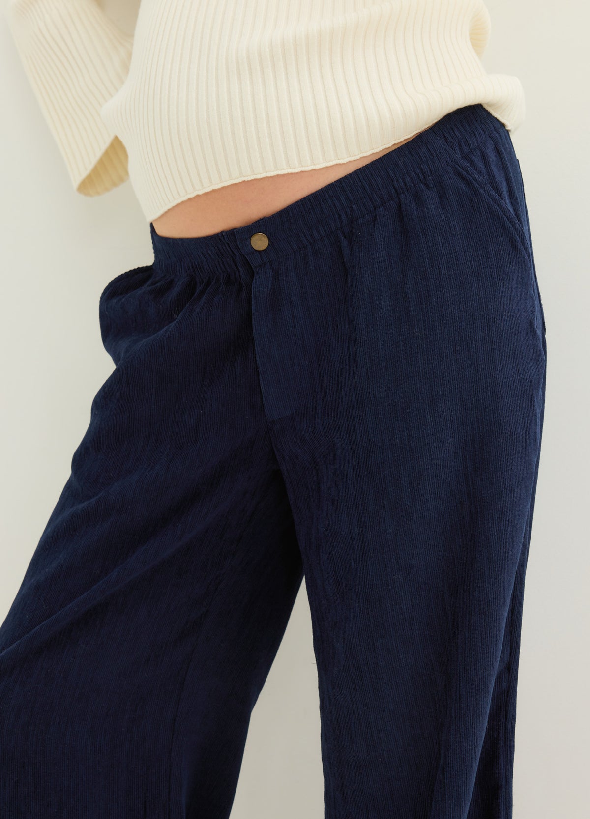 Navy maternity corduroy pants with a flexible waistband, shown on a pregnant model beneath a cream sweater.