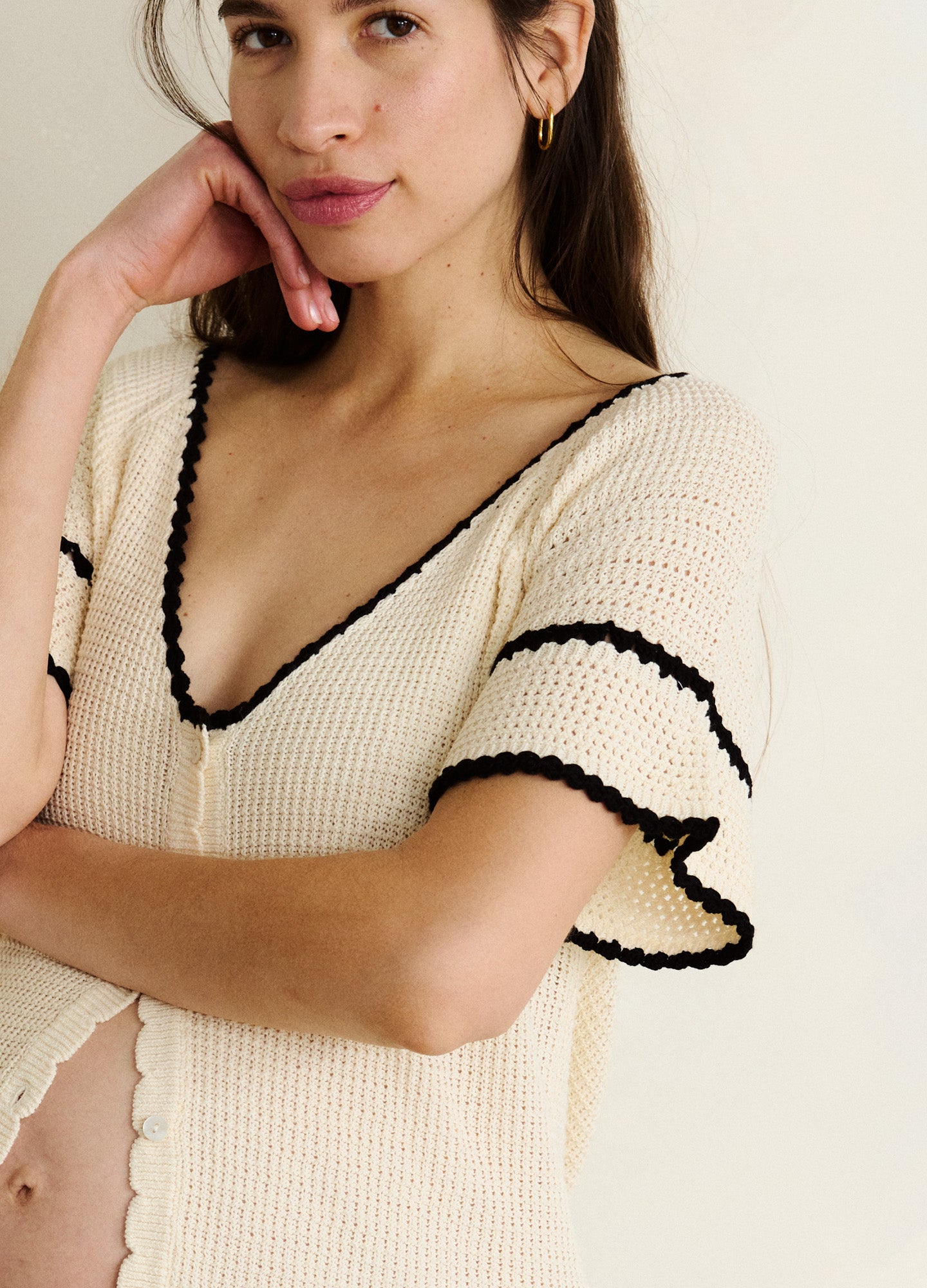 Cream crochet maternity cardigan with black edging and ruffle sleeves, soft knit texture.