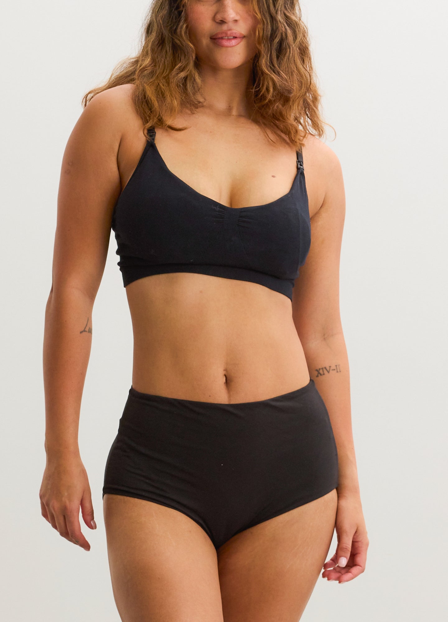 Black seamless nursing and pumping bra with adjustable thin straps on a model.