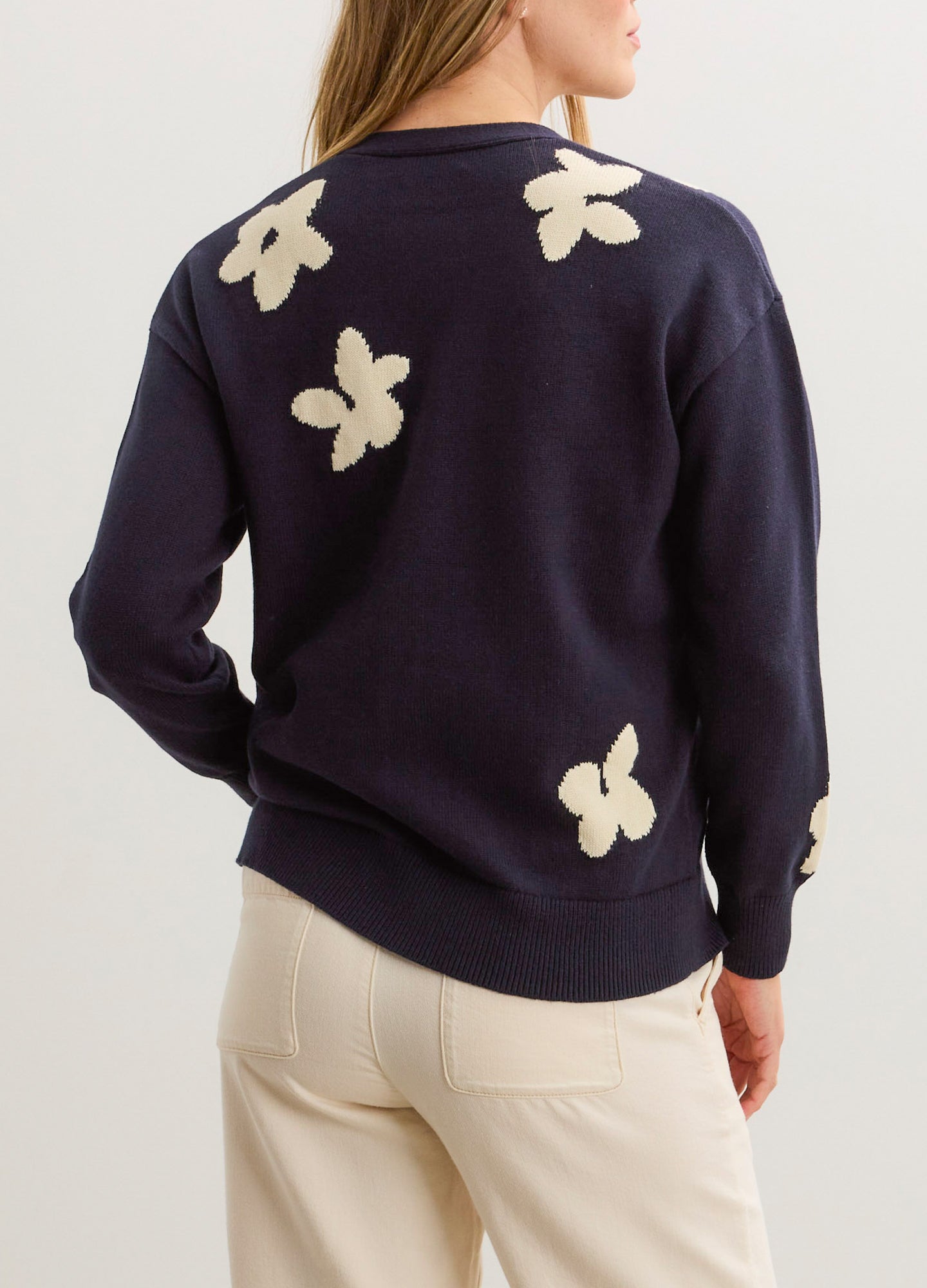 Navy oversized cardigan with cream floral jacquard patterns on the back and sleeves, soft knit fabric.